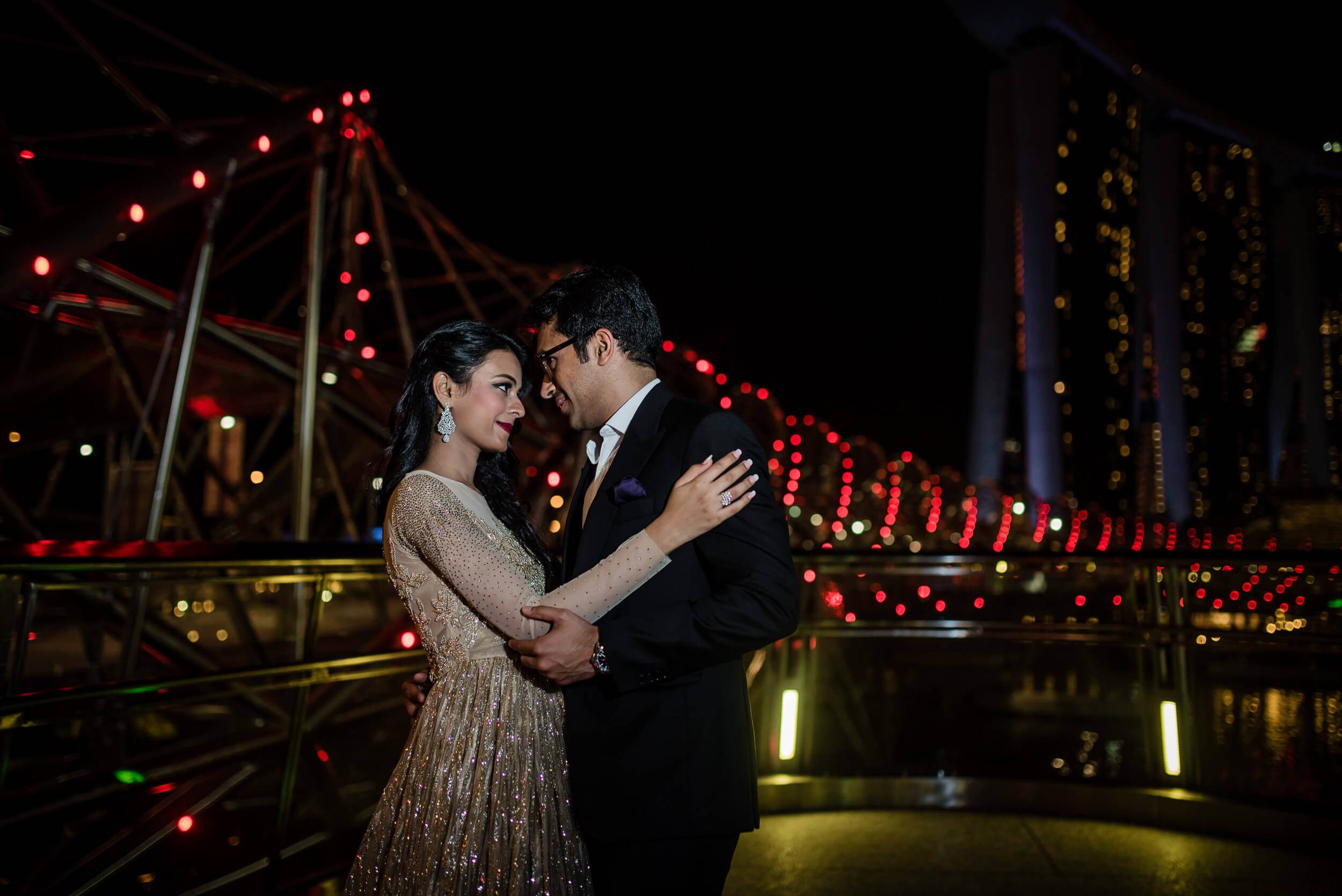 Yash and Disha embrace under glowing carnival lights at night in Singapore