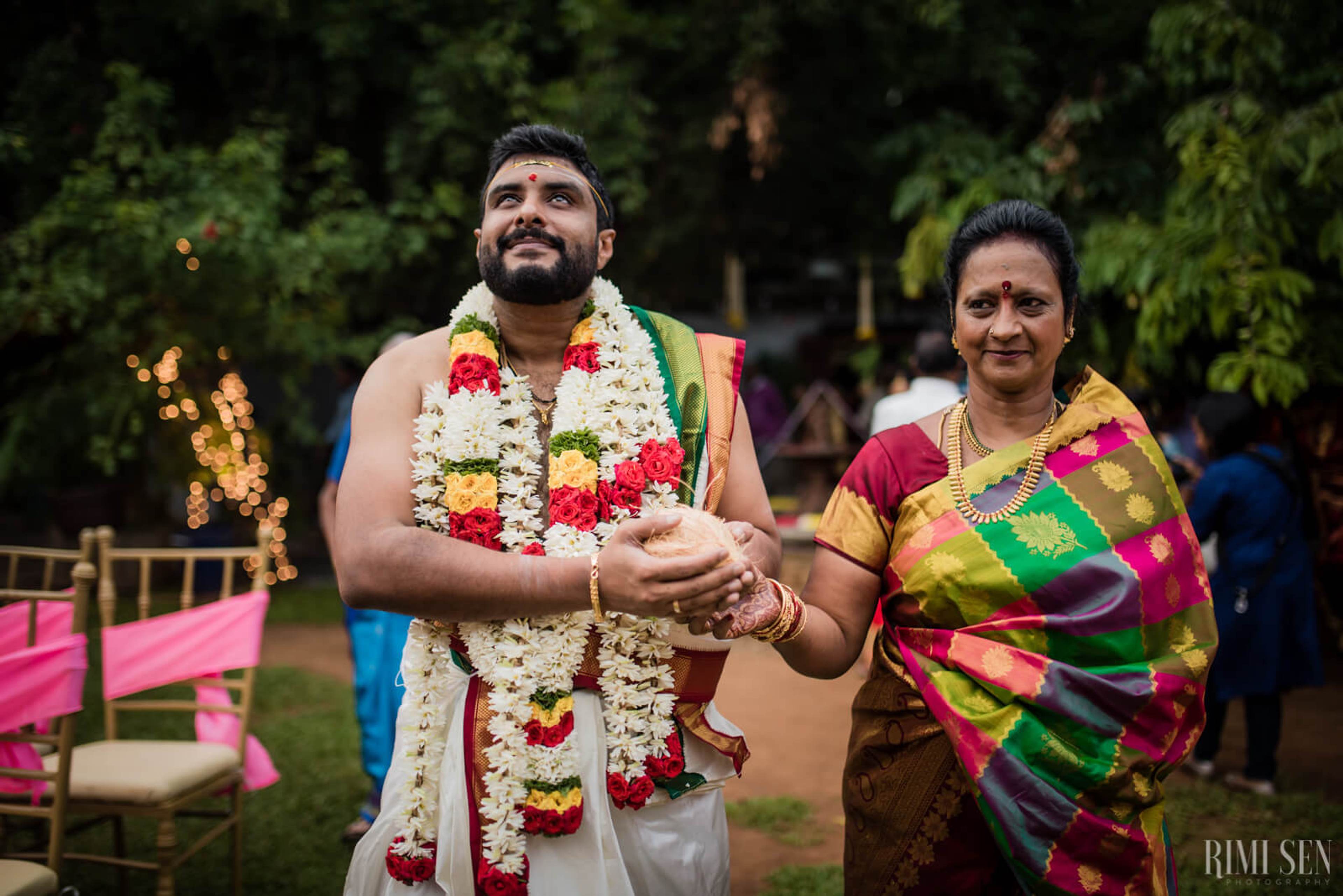 Sridhar wearing colorful flower garland and woman in vibrant silk sari at outdoor Bangalore celebration
