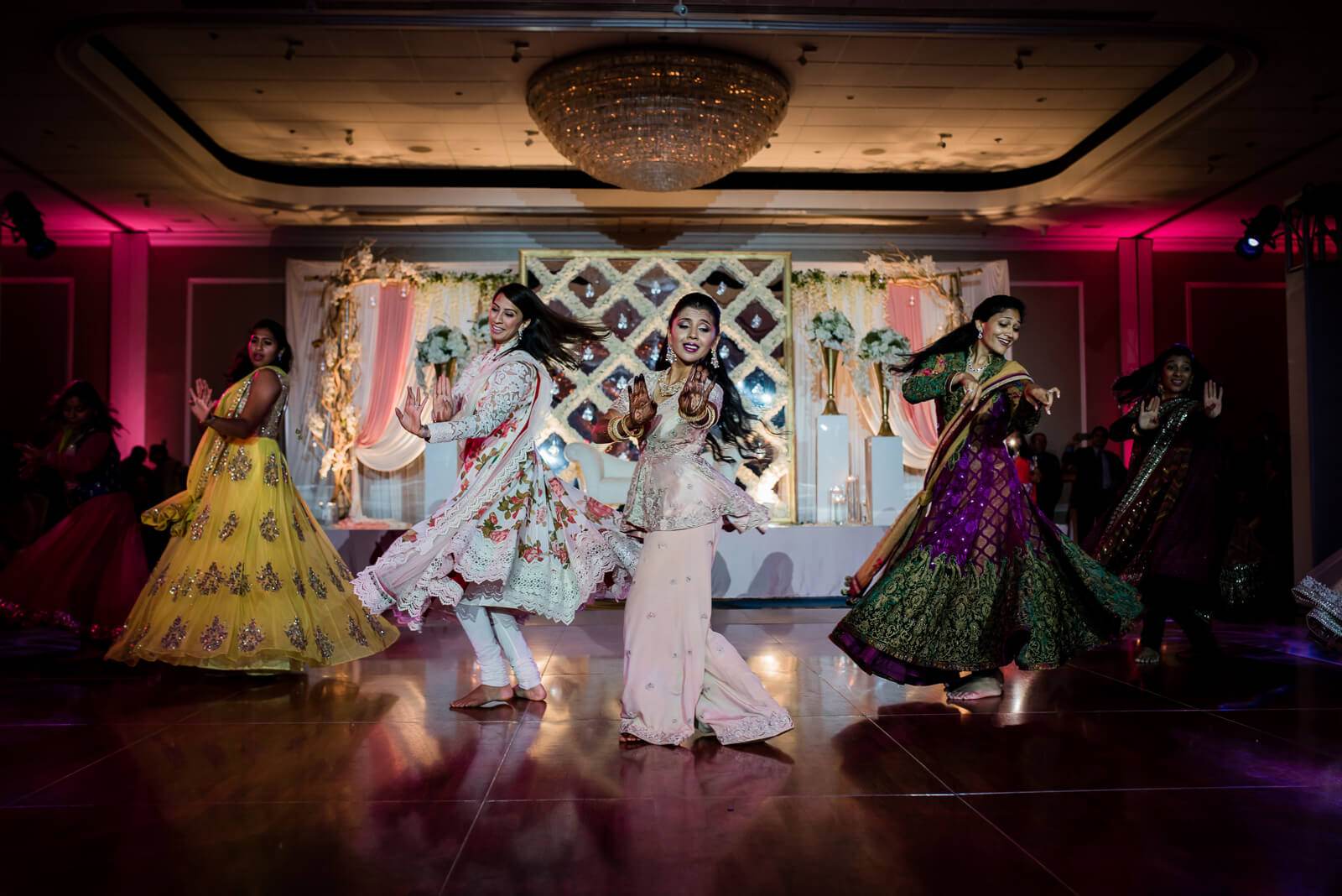 Barkha and Ankit dance with wedding guests in vibrant traditional attire at New York reception venue