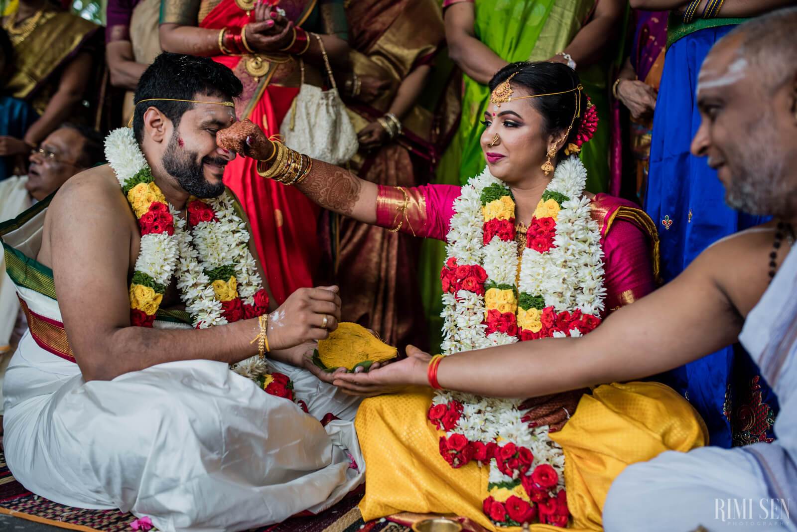 Nivetha and Sridhar exchange garlands during their traditional wedding ceremony in Bangalore, surrounded by family