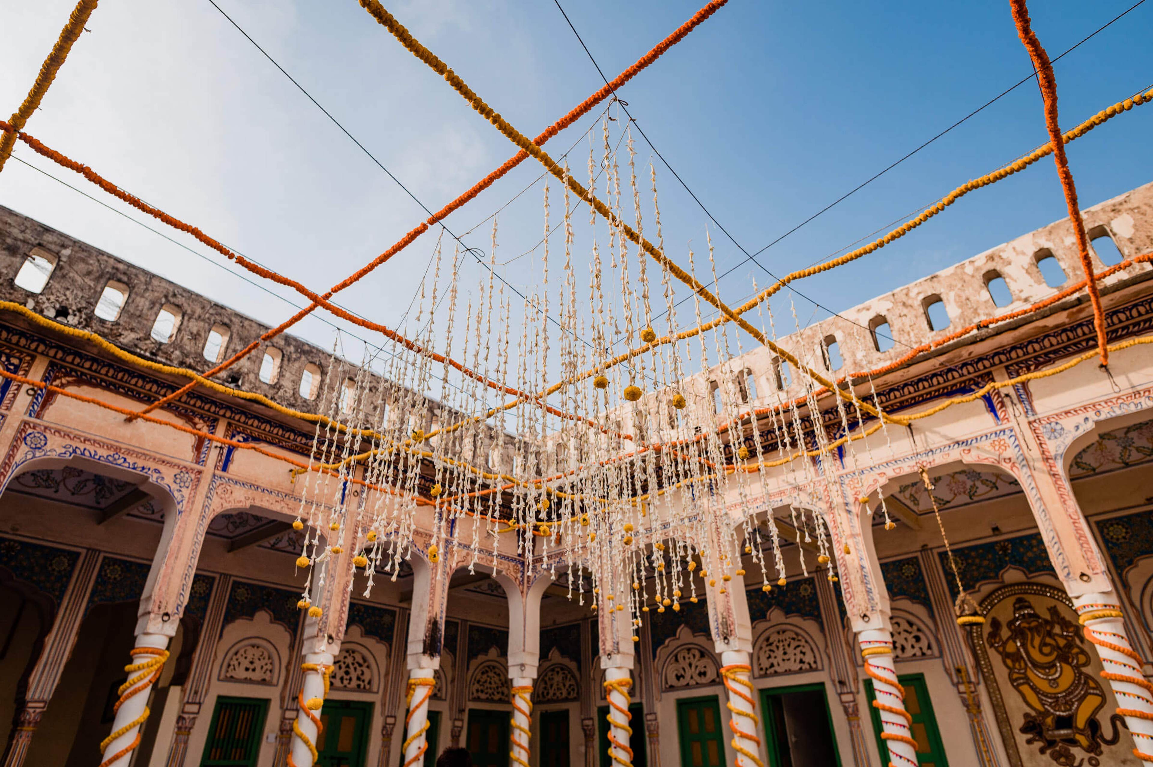 Ornate Rajasthani courtyard with hanging floral installations and decorative rope framework overhead