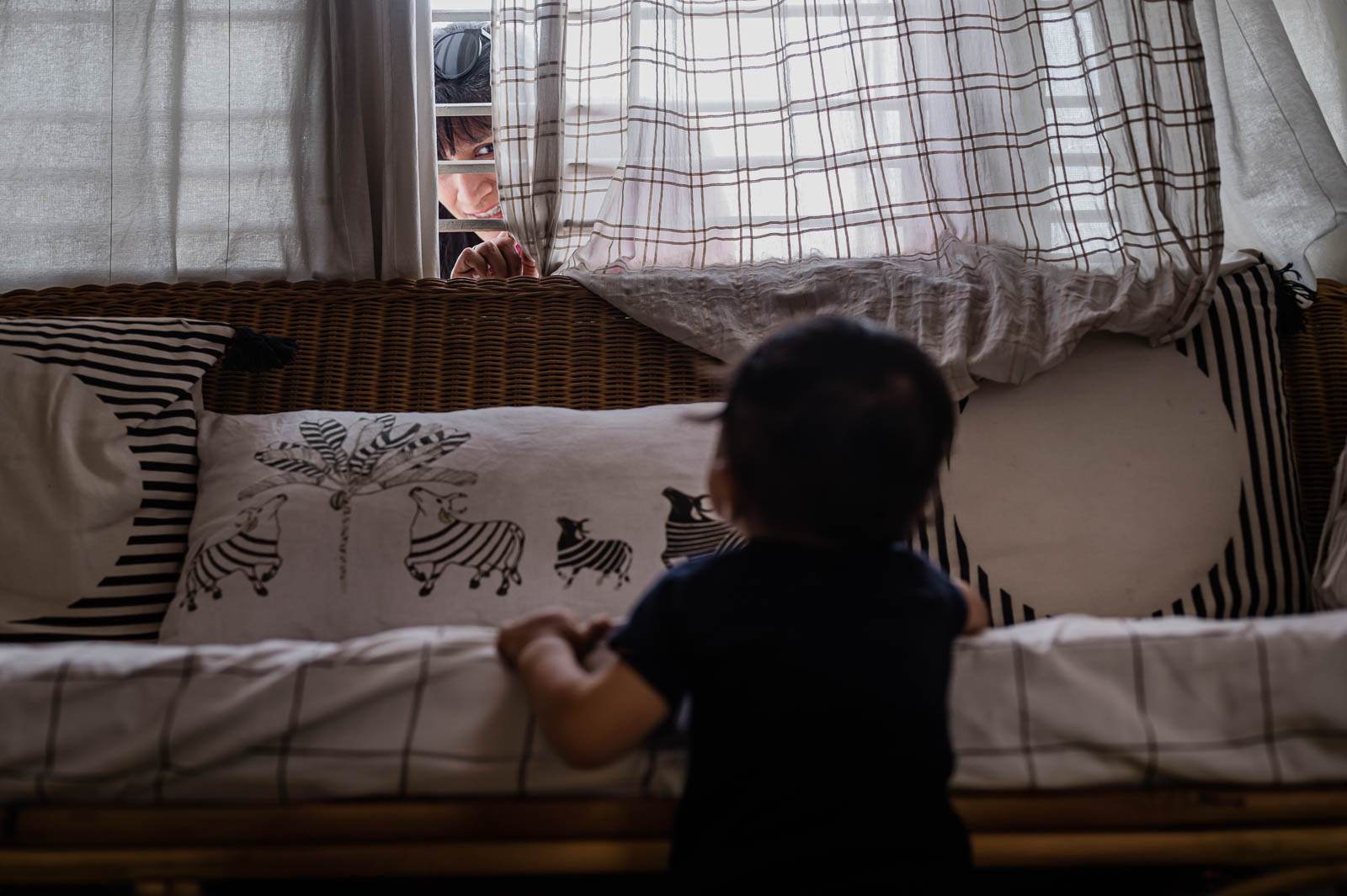 Child in dark clothing viewed from above on bed with patterned pillows and sheer canopy