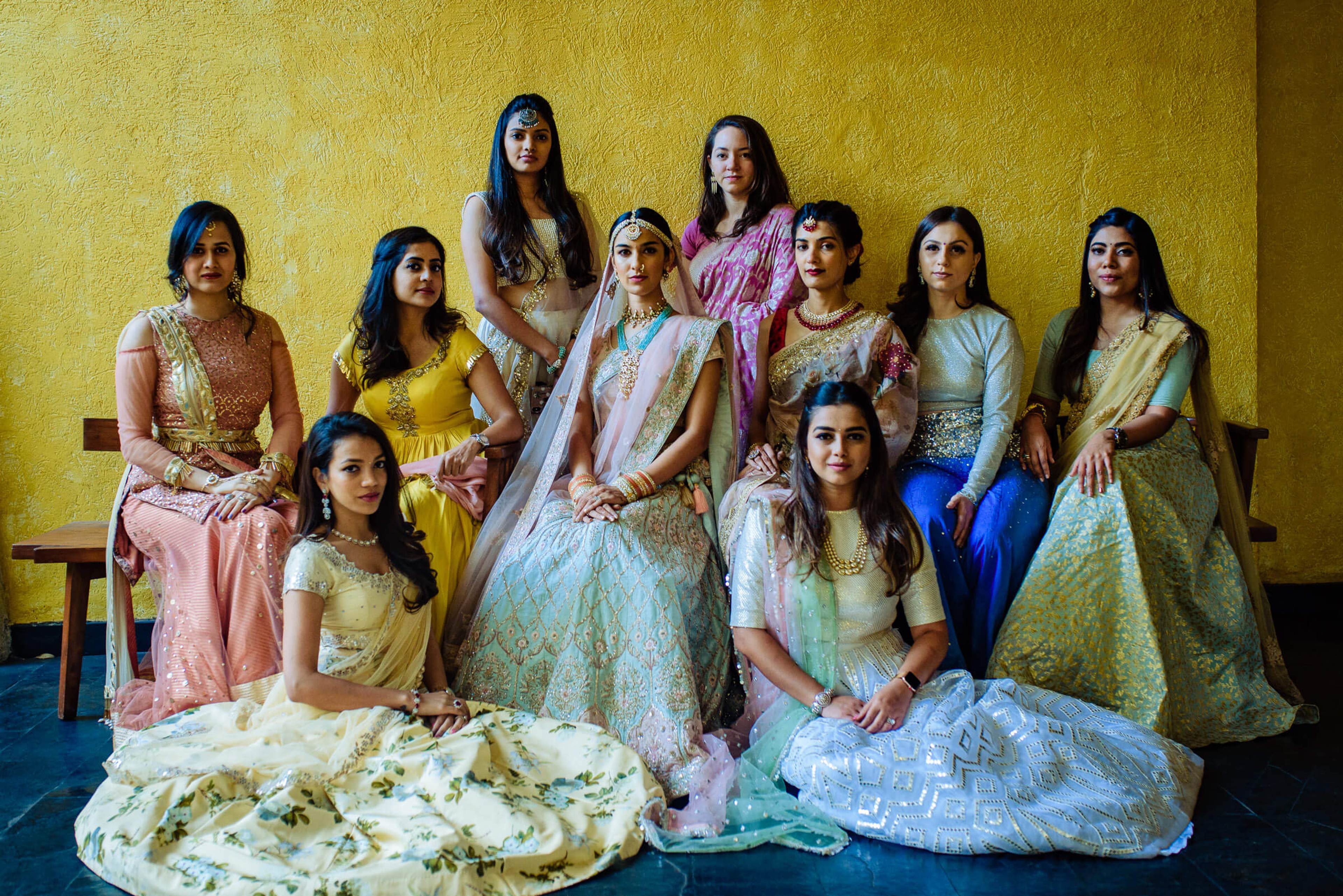 Shreya with ten women in traditional Indian attire against a yellow wall at Mahabaleshwar