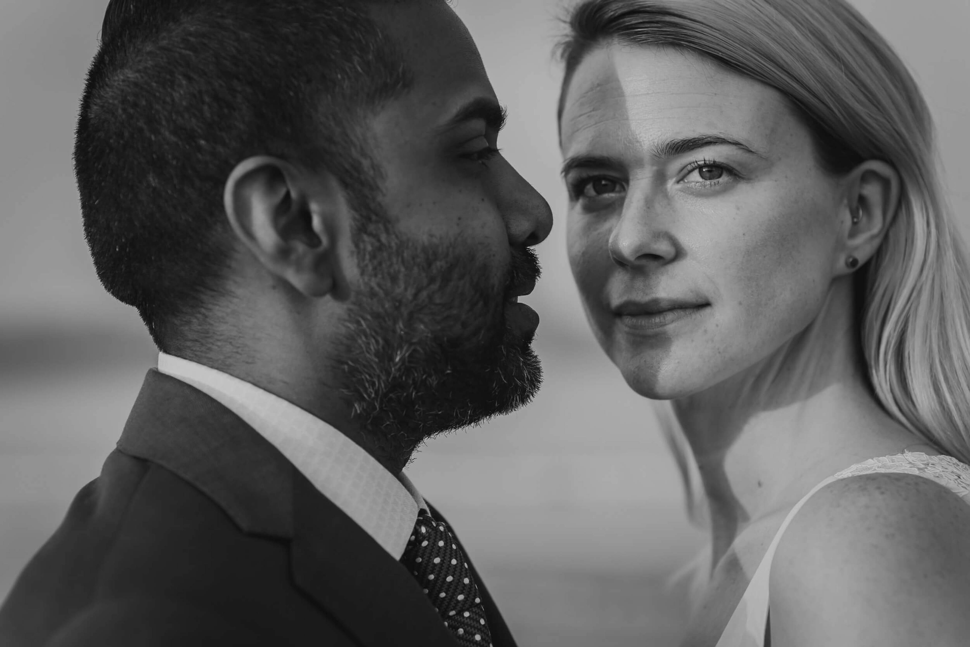 Sarah and Ravin in profile, black and white portrait, formal attire against neutral background