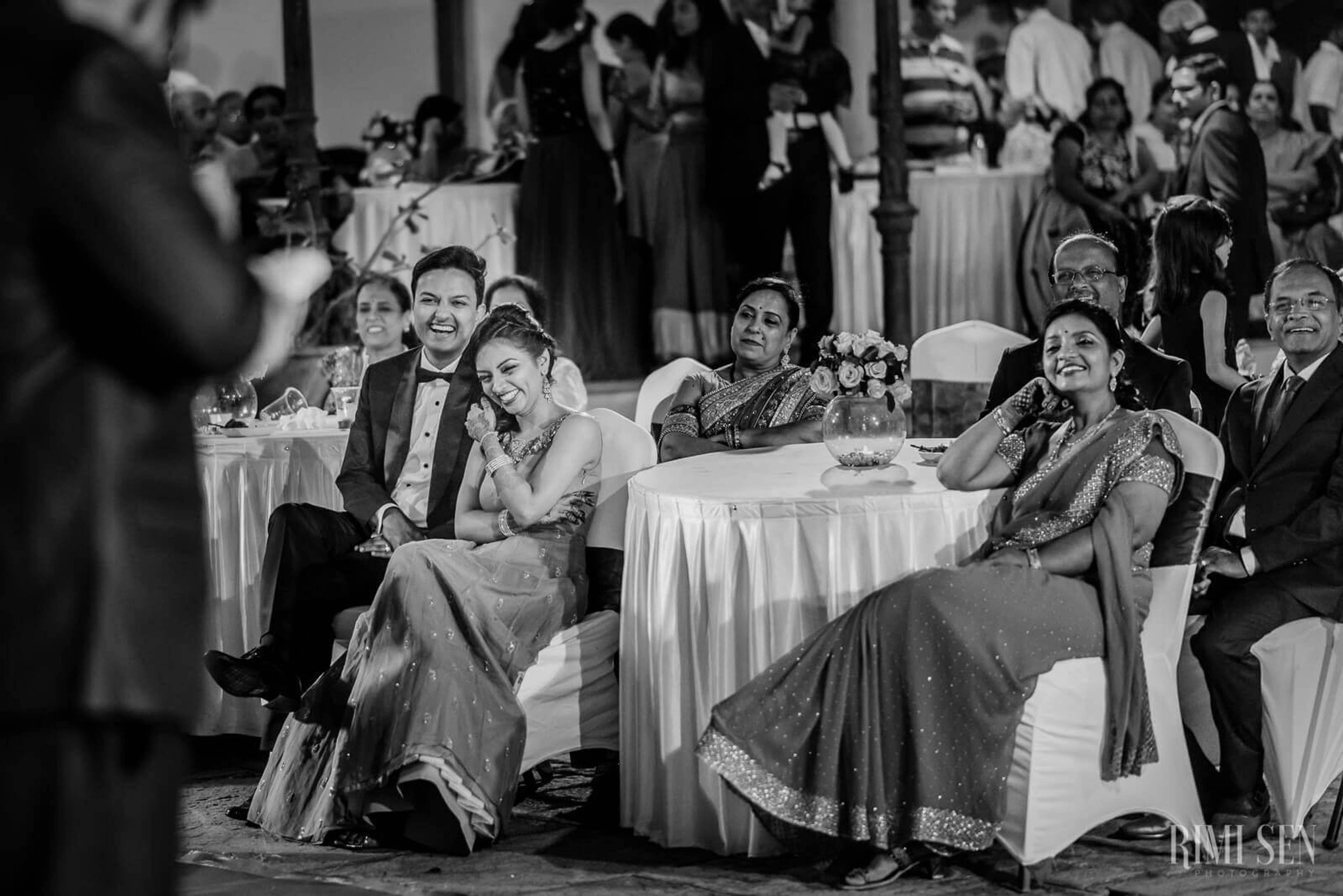 Pooja and Aniket seated with guests at their Bangalore wedding reception, black and white
