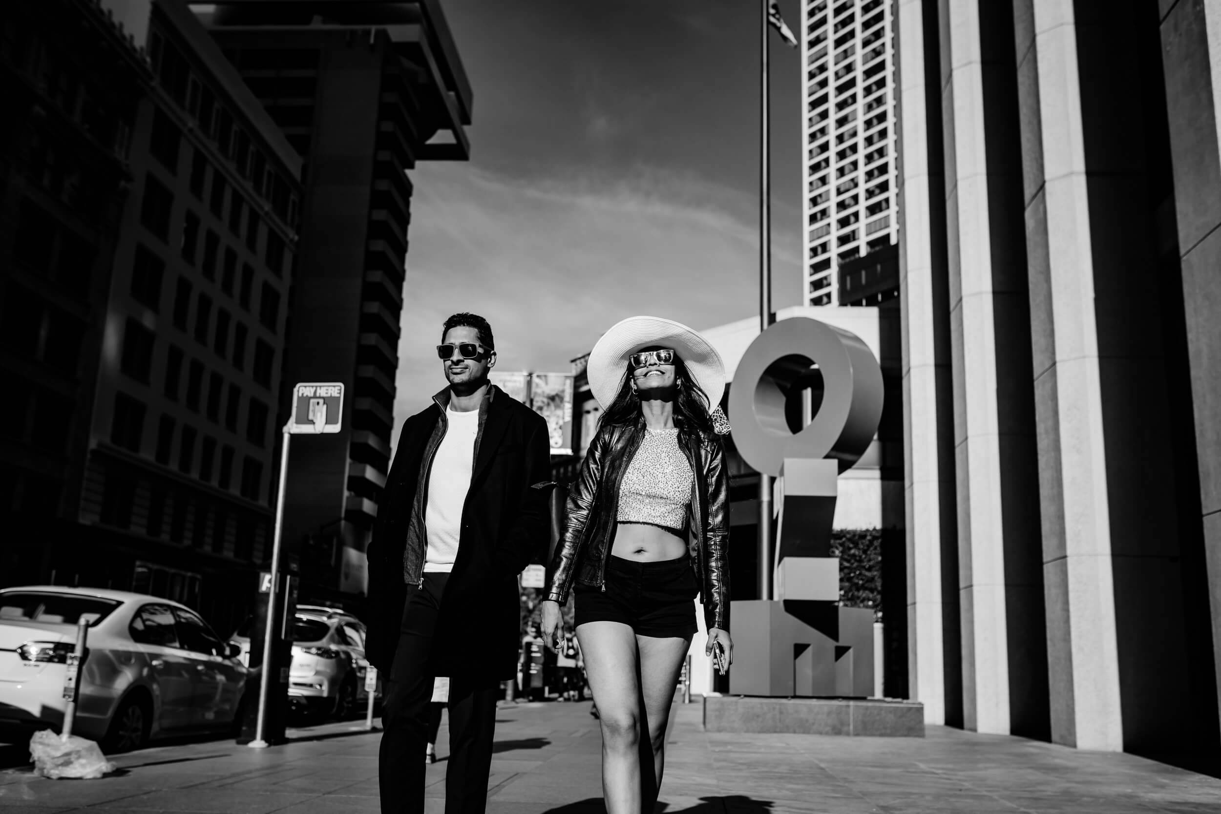 Anu and Raghu stand on an urban street in California, wearing sunglasses and stylish black leather jackets