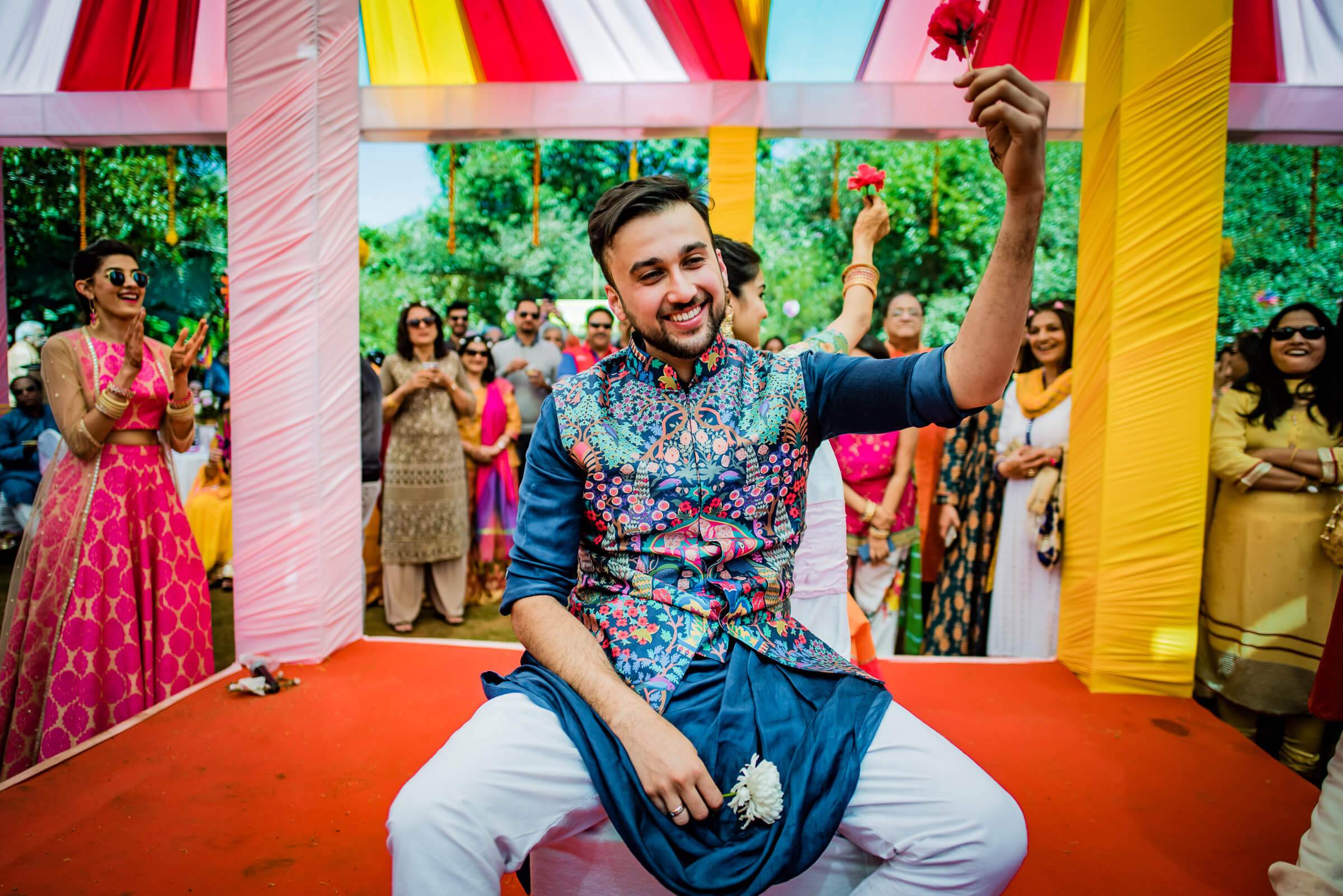 Yash celebrates on vibrant orange platform beneath colorful ribbons at Mahabaleshwar wedding