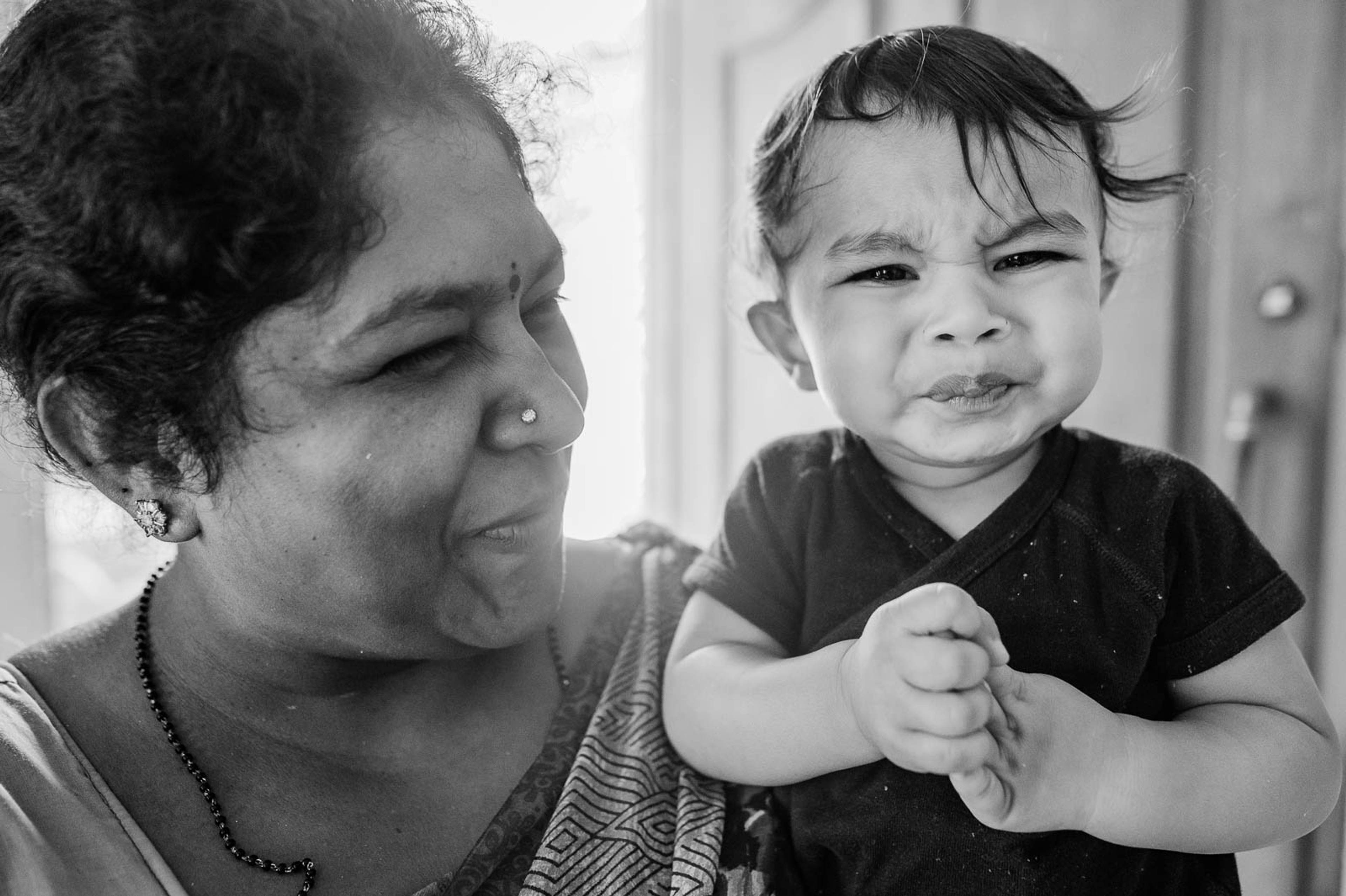 Woman and smiling toddler in black-and-white portrait, intimate indoor moment