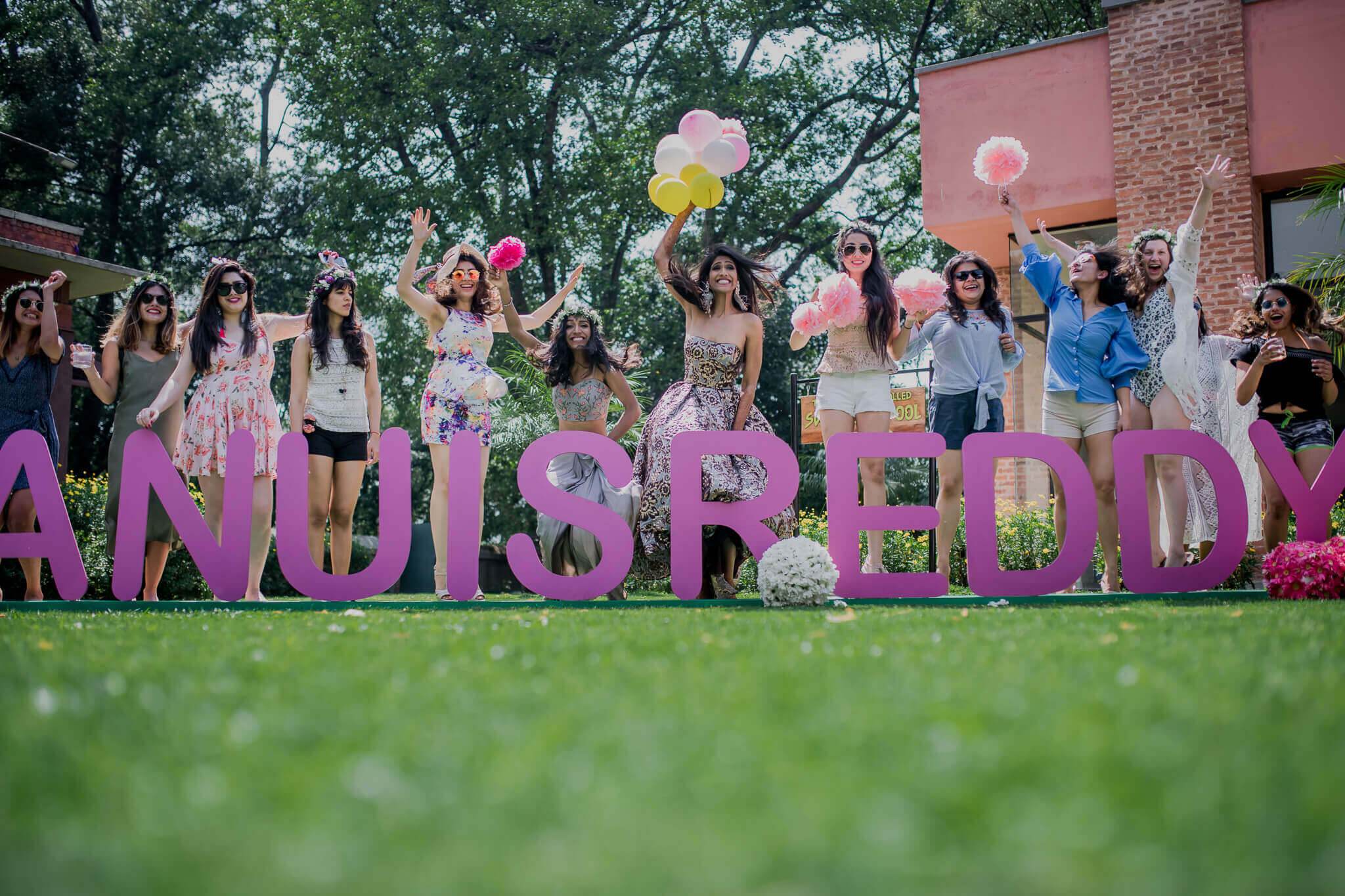Anu and Raghu's wedding guests hold colorful balloons behind large purple letters at Nepal venue