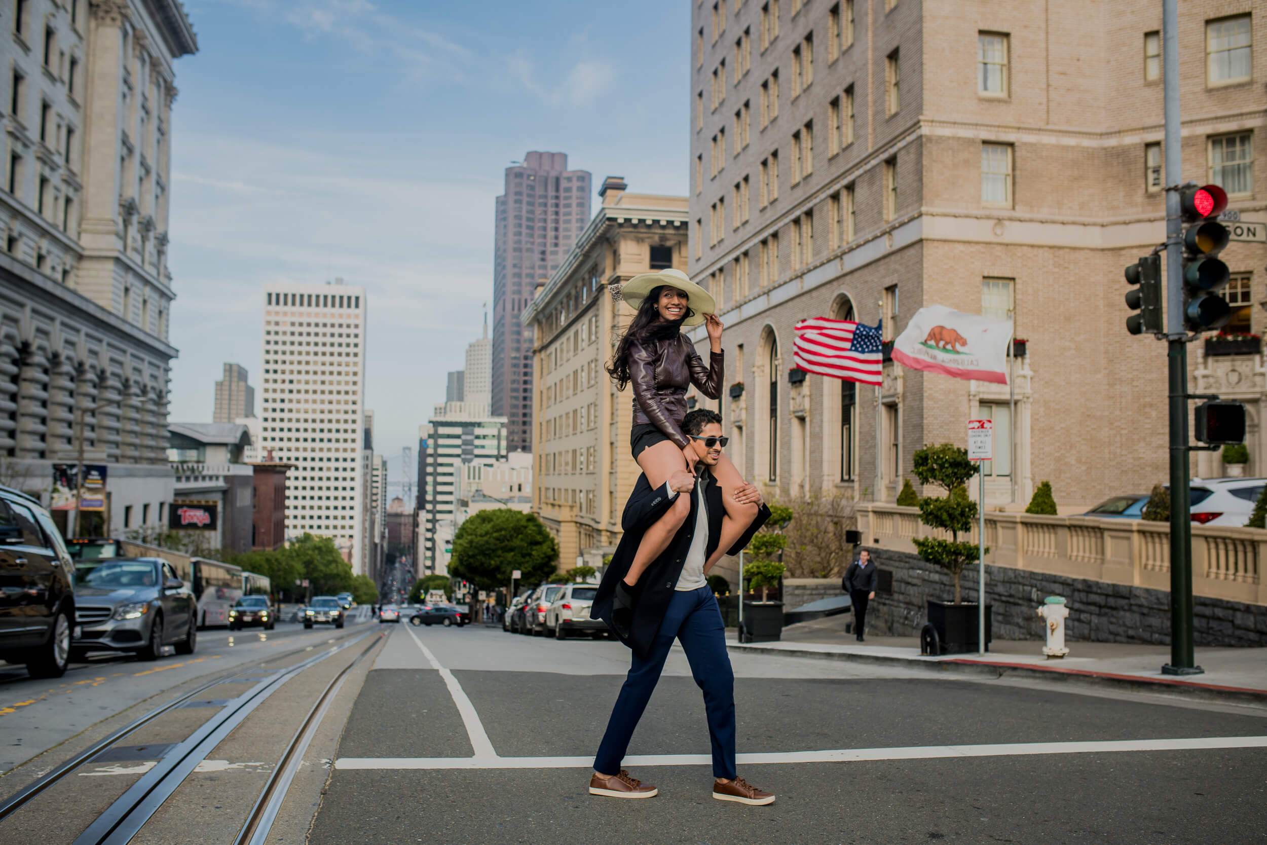 Anu lifted high by Raghu on a San Francisco street lined with historic buildings and American flags