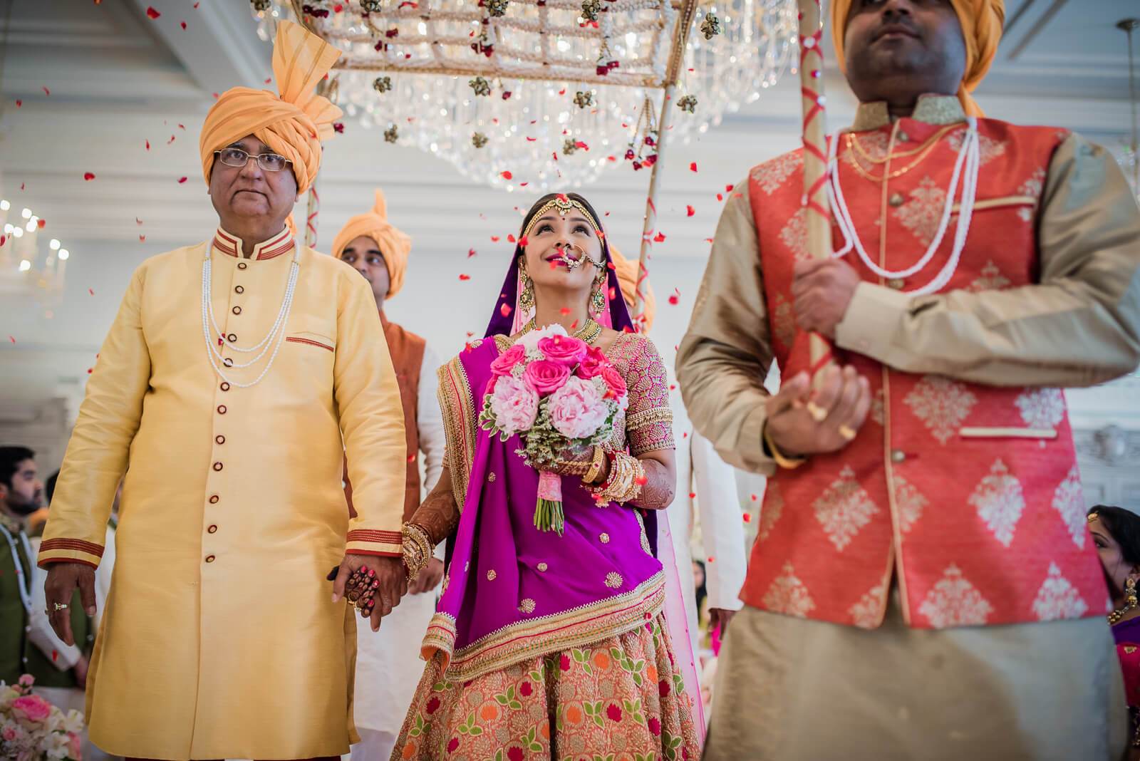 Barkha and Ankit exchange vows under falling flower petals in traditional Indian wedding attire at New York ceremony