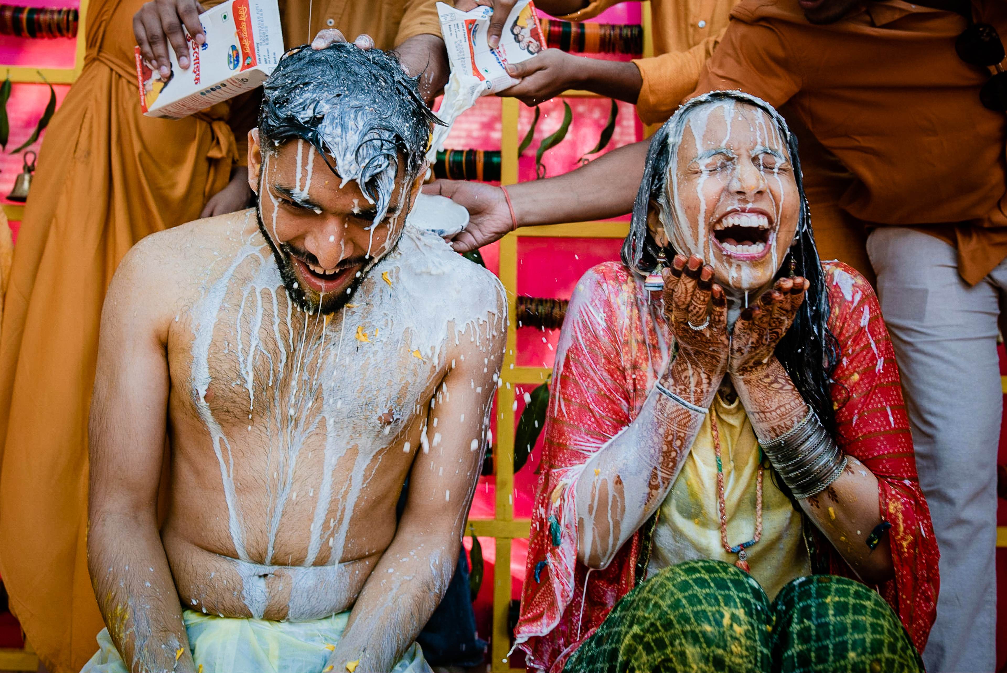 Avani and Srikant covered in colored powder, laughing joyfully during Holi celebration in Goa
