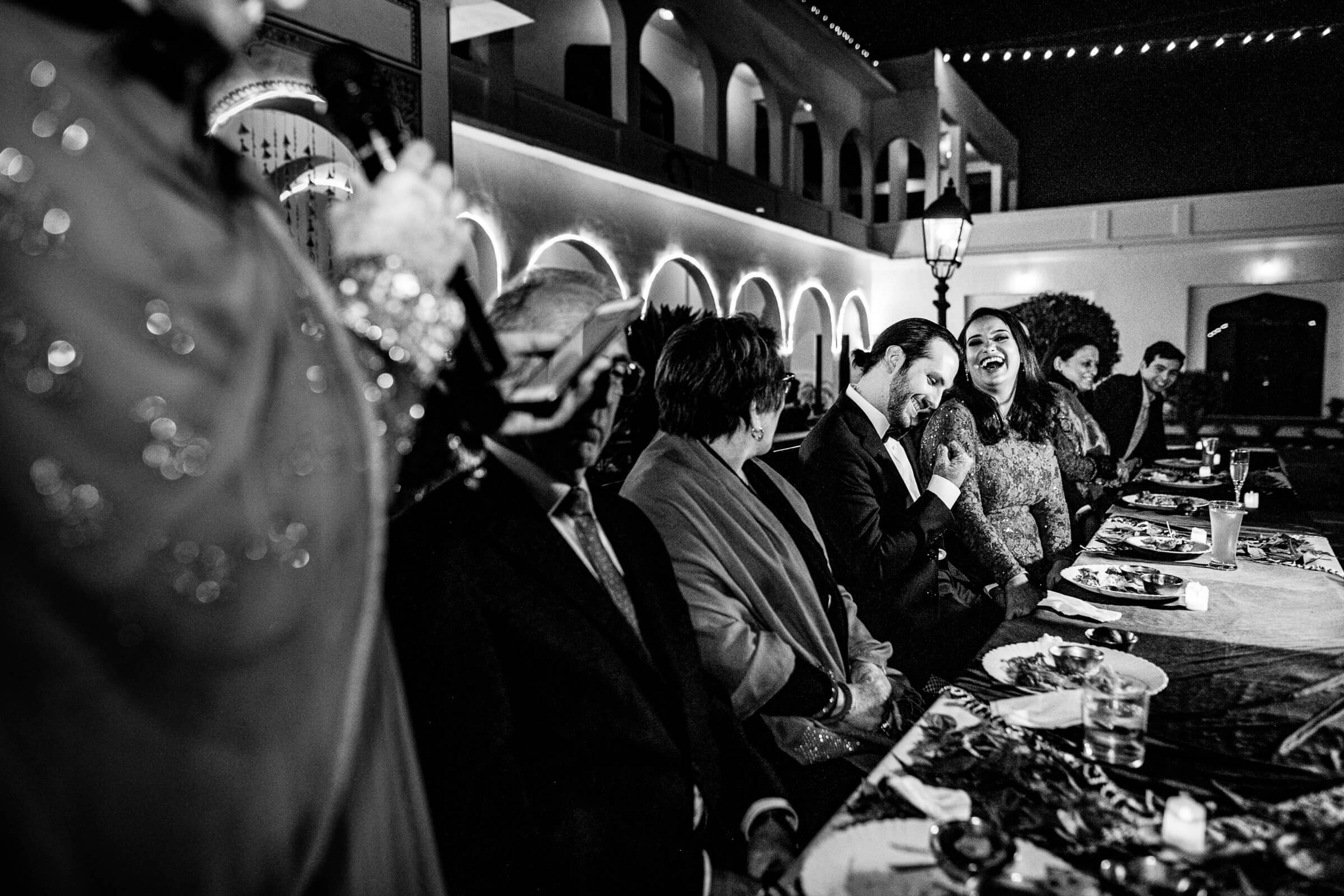 Guests seated at long table during evening reception in Rajasthan, black and white