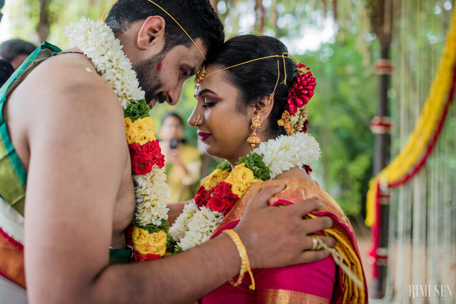Nivetha and Sridhar embrace wearing colorful flower garlands at their Bangalore wedding ceremony