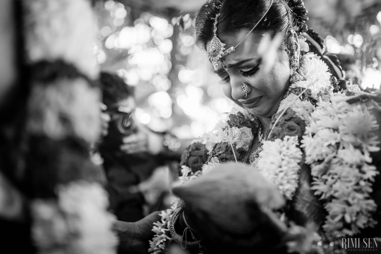 Nivetha in elaborate white floral garland, looking down with soft expression, black and white portrait