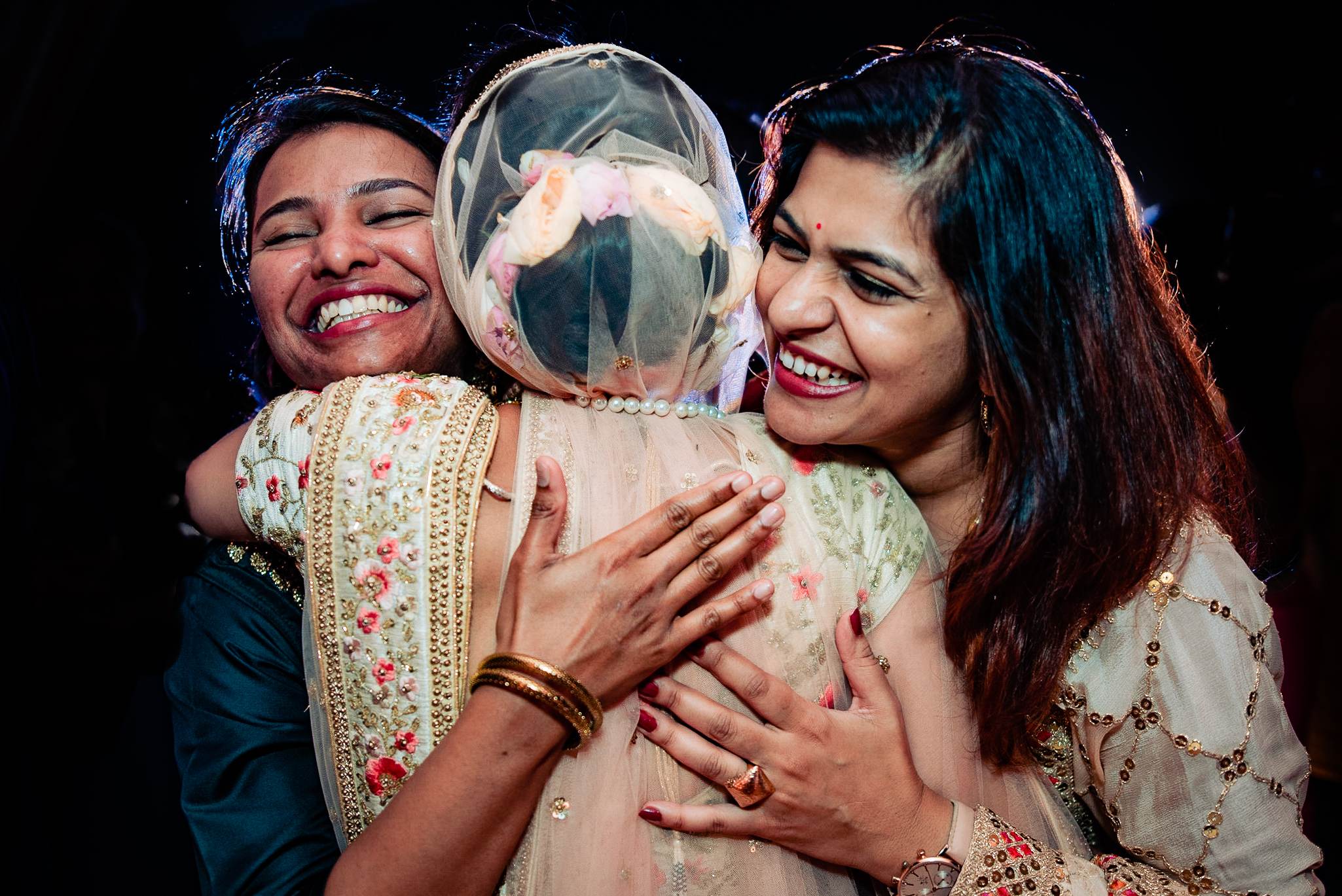 Avani and Srikant hold their laughing baby in traditional attire against a dark background in Goa