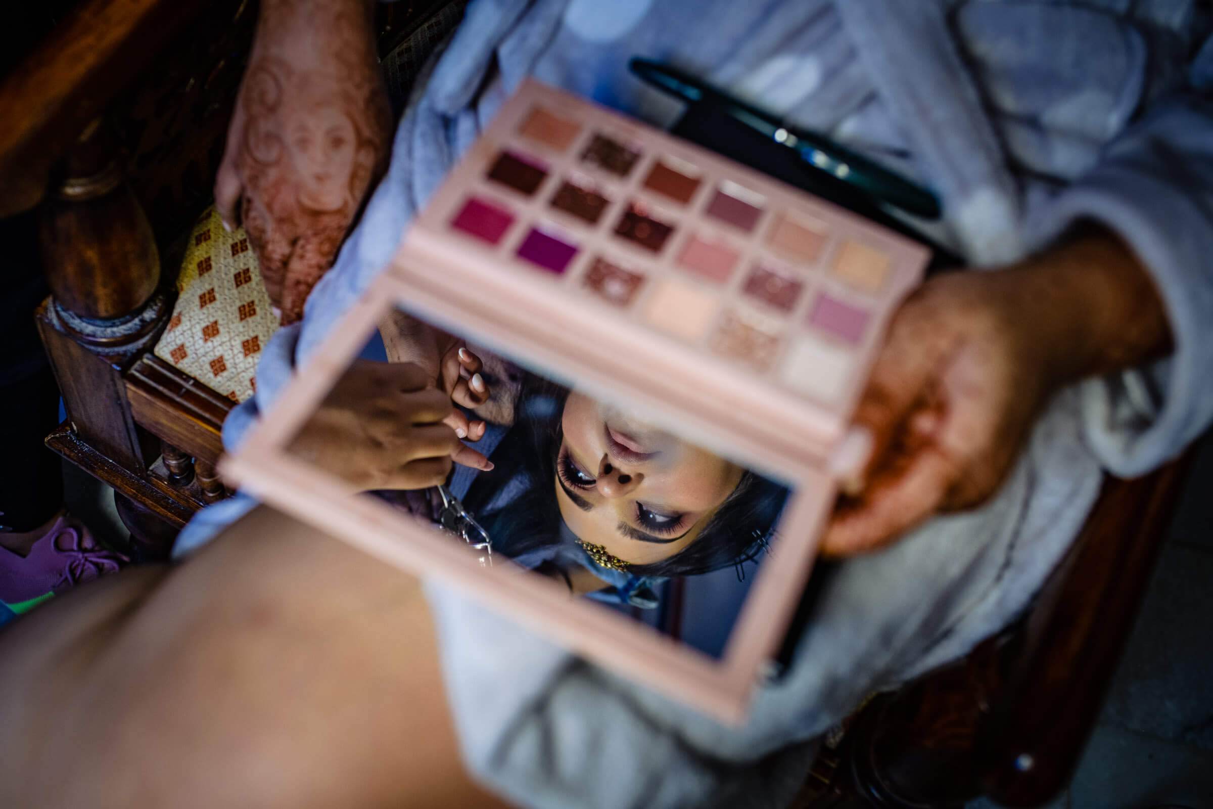 Maitrayee and Eric's makeup artist holds open eyeshadow palette during Rajasthan wedding preparations