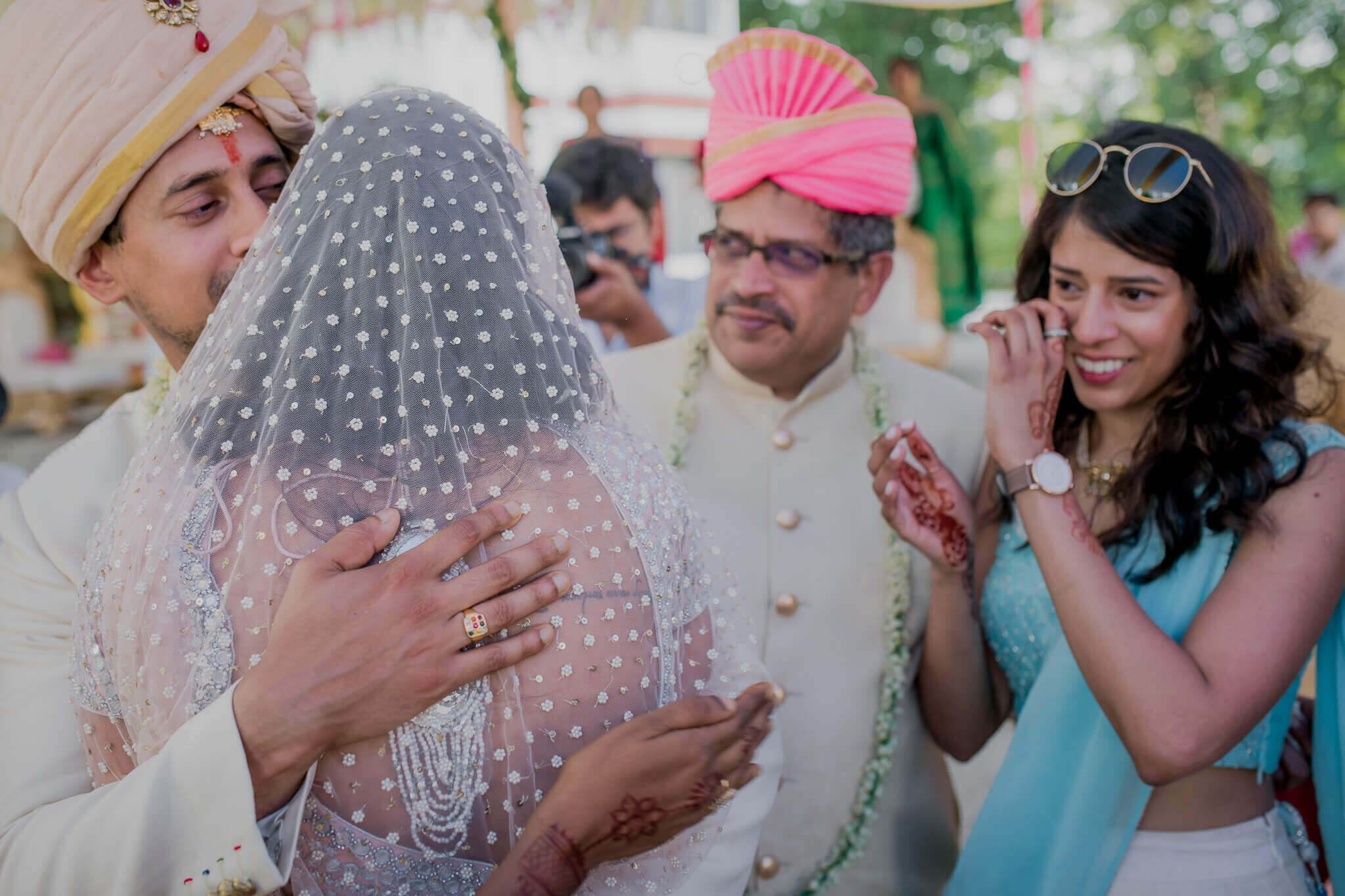 Anu and Raghu embrace during their Nepal wedding ceremony, surrounded by smiling guests in traditional attire