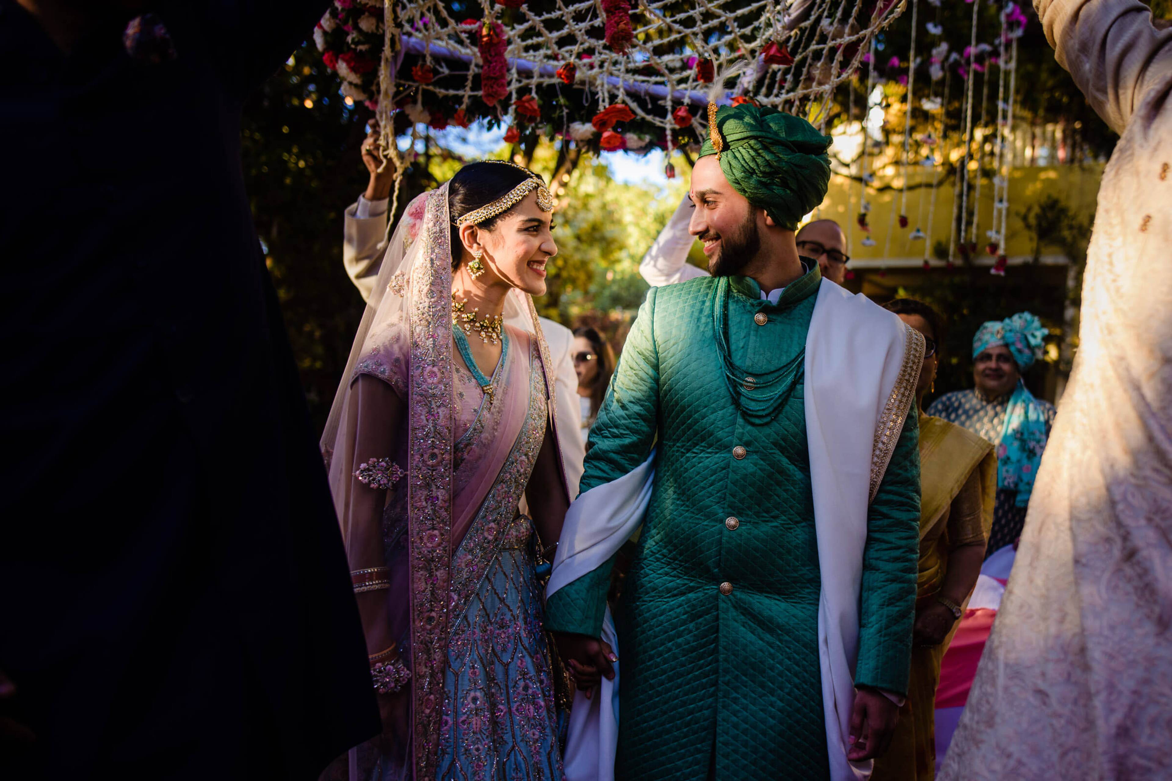 Shreya in purple lehenga and Yash in teal sherwani laugh together under illuminated mandap at Mahabaleshwar wedding