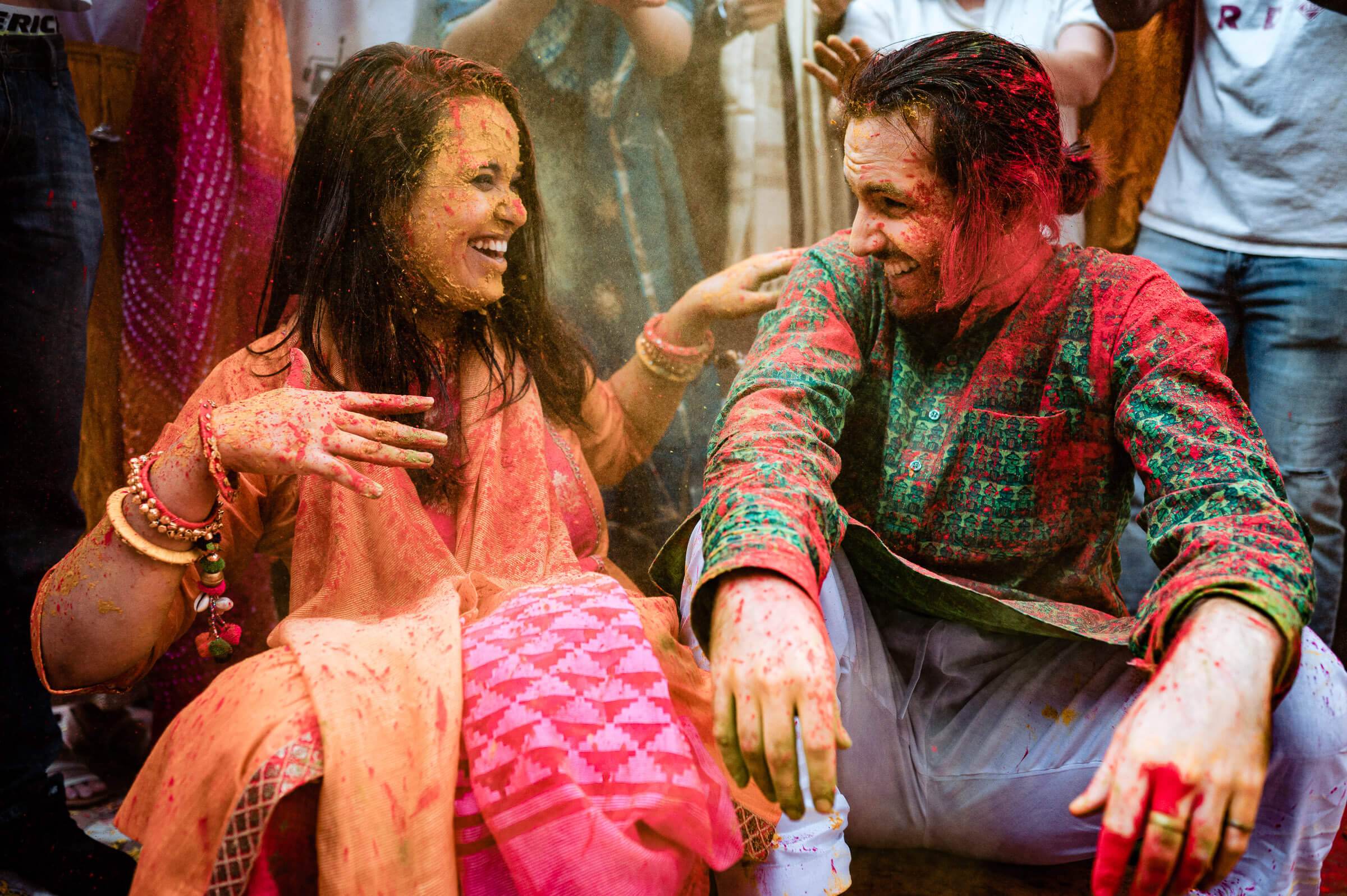 Maitrayee and Eric laughing together covered in colored powder during Holi celebration in Rajasthan