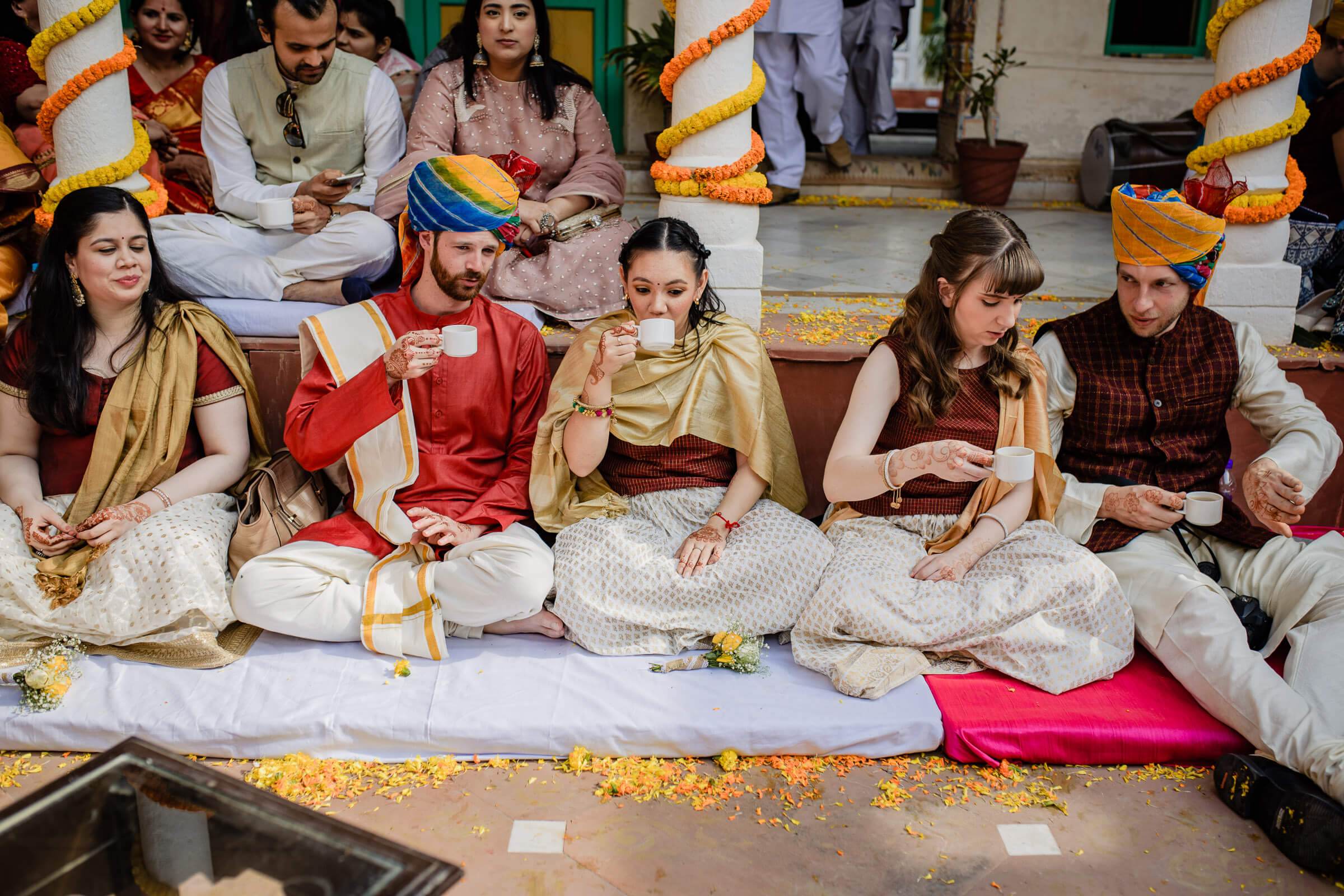 Maitrayee and Eric celebrate with family during a traditional Rajasthani wedding ceremony, surrounded by marigold garlands