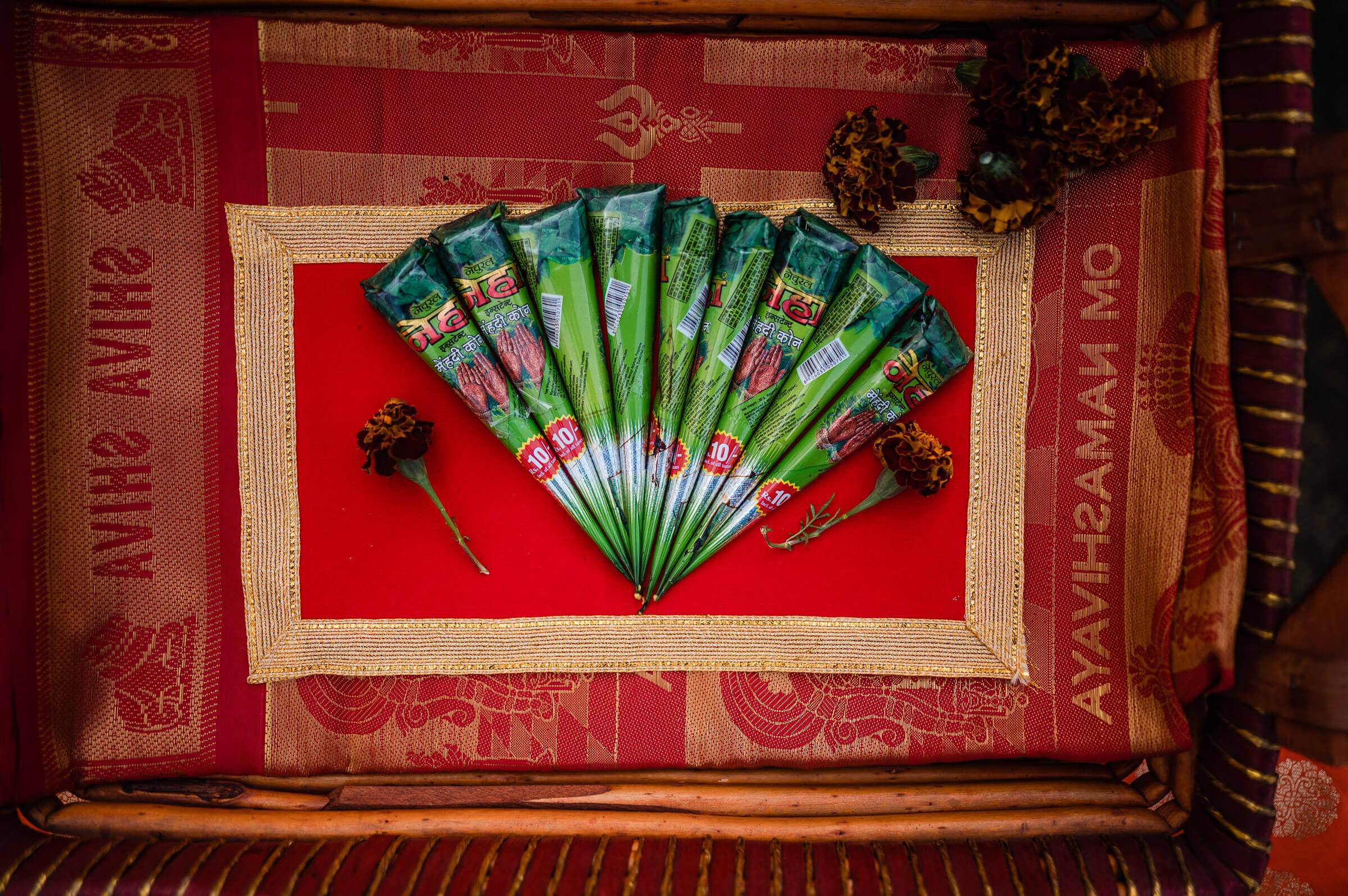 Ornate green fan with decorative packaging arranged on red fabric, Rajasthan wedding detail shot