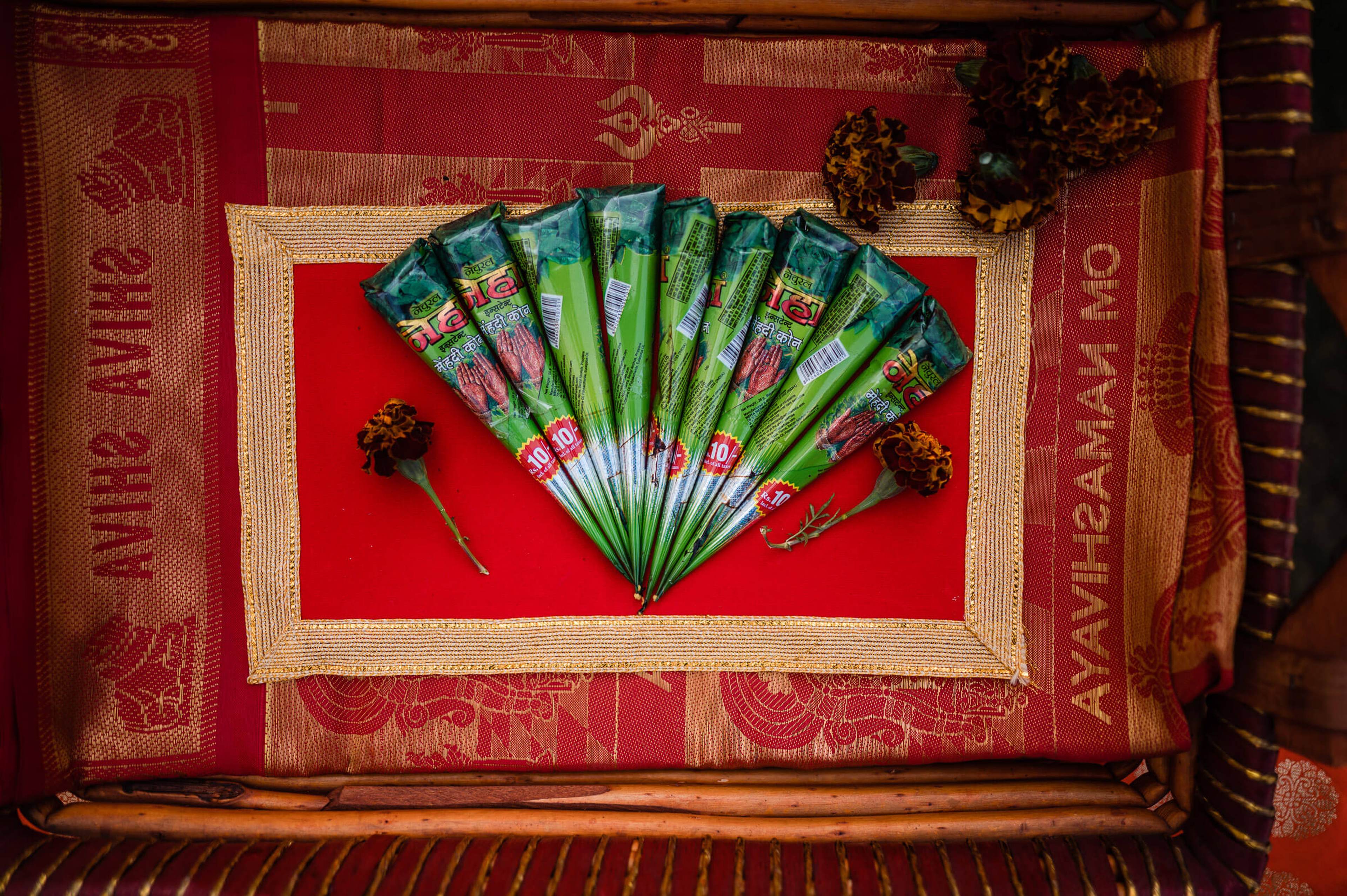 Ornate green fan with decorative packaging arranged on red fabric, Rajasthan wedding detail shot