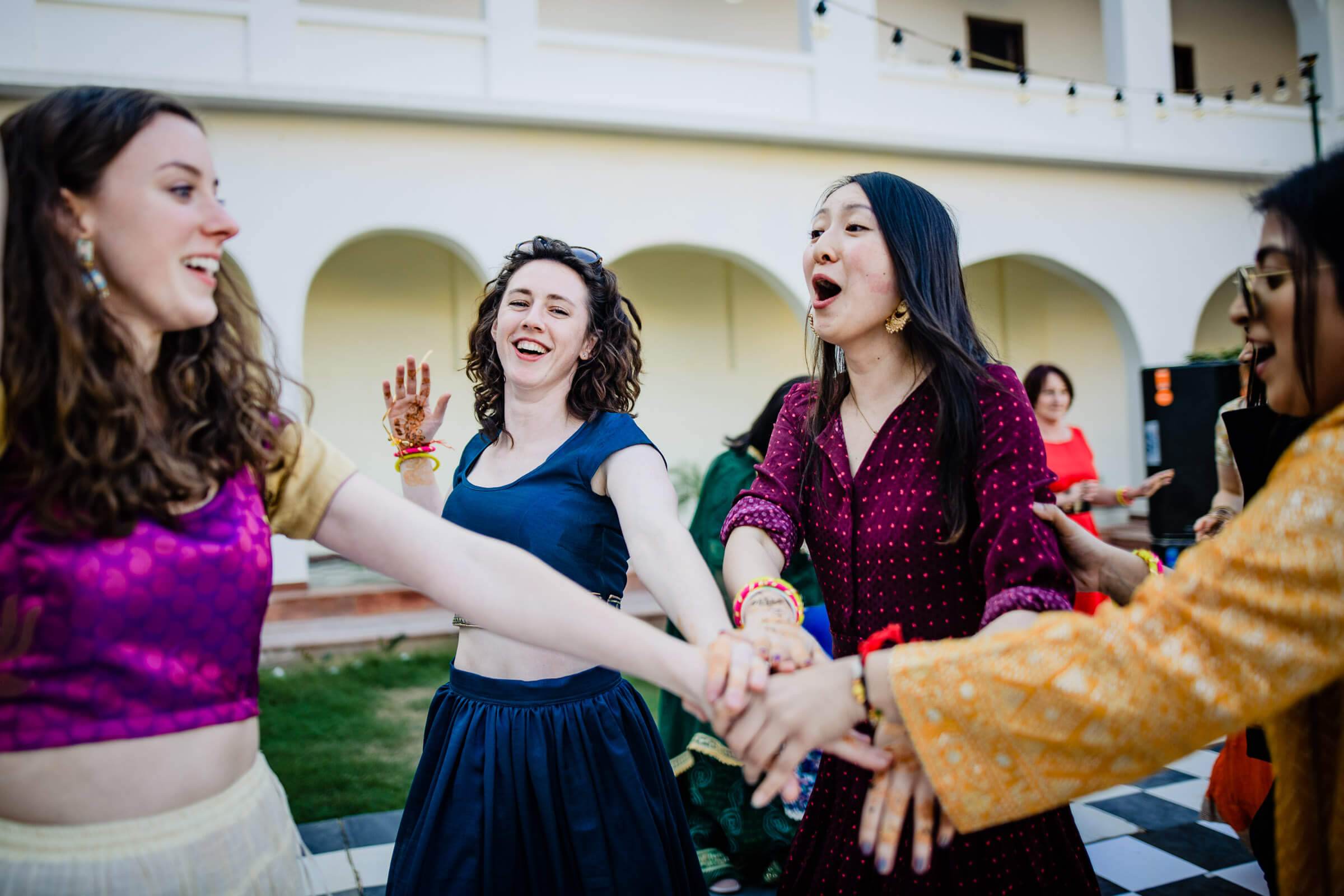 Maitrayee and Eric's guests celebrate together at their Rajasthan wedding, dancing and laughing in colorful attire