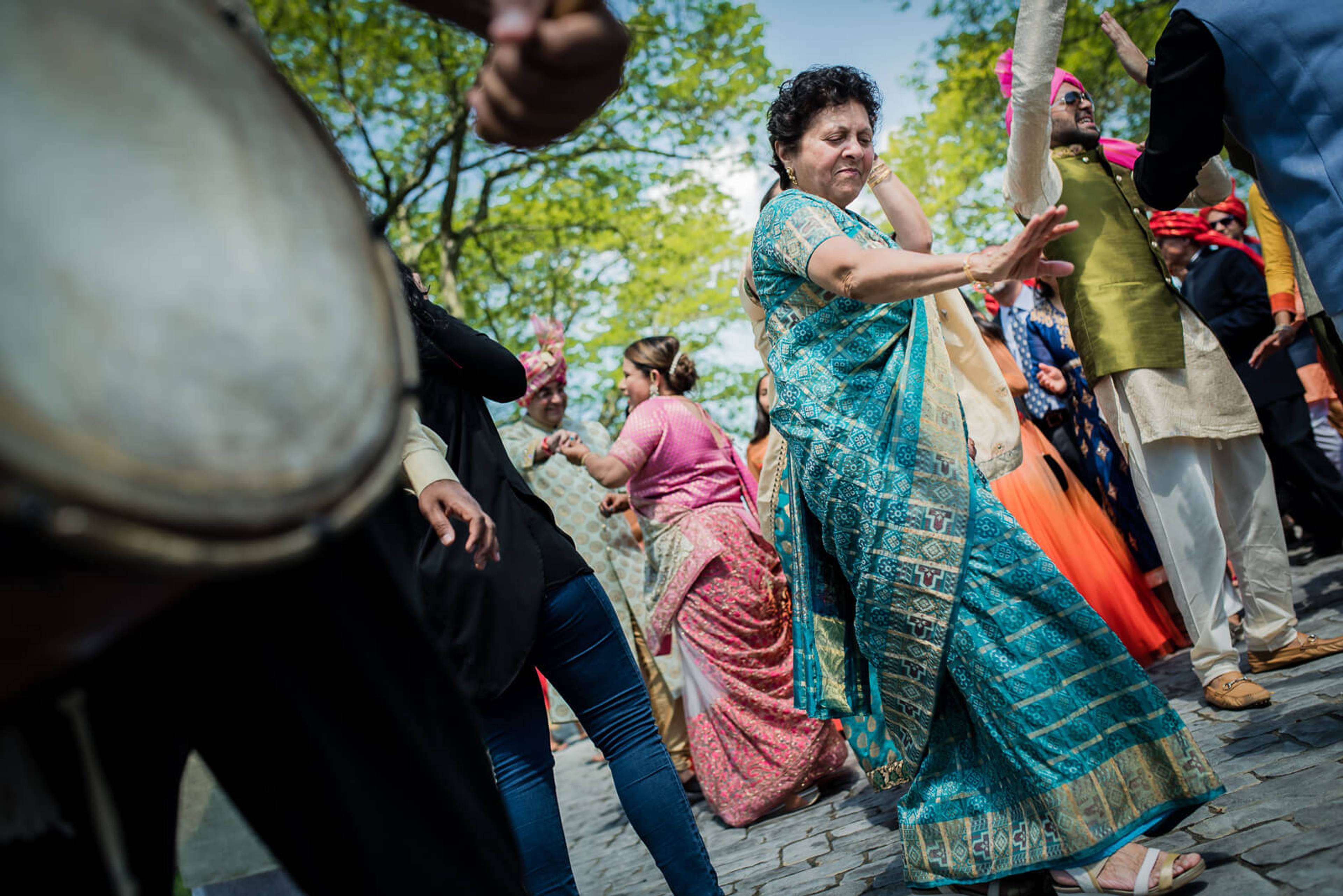 Barkha in turquoise sari dancing with guests in colorful attire at New York celebration