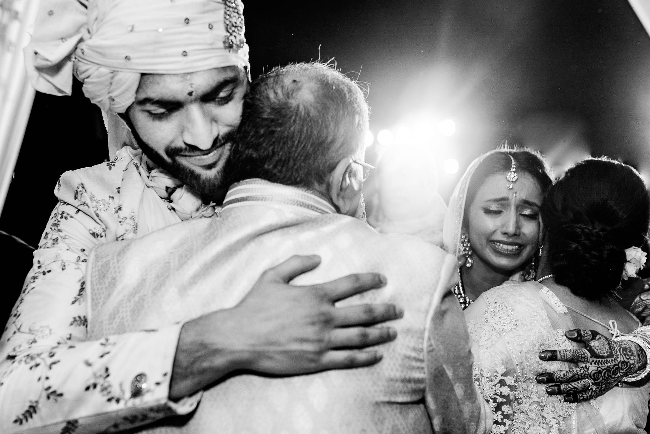 Avani & Srikant embrace family members during celebration in Goa, black and white portrait