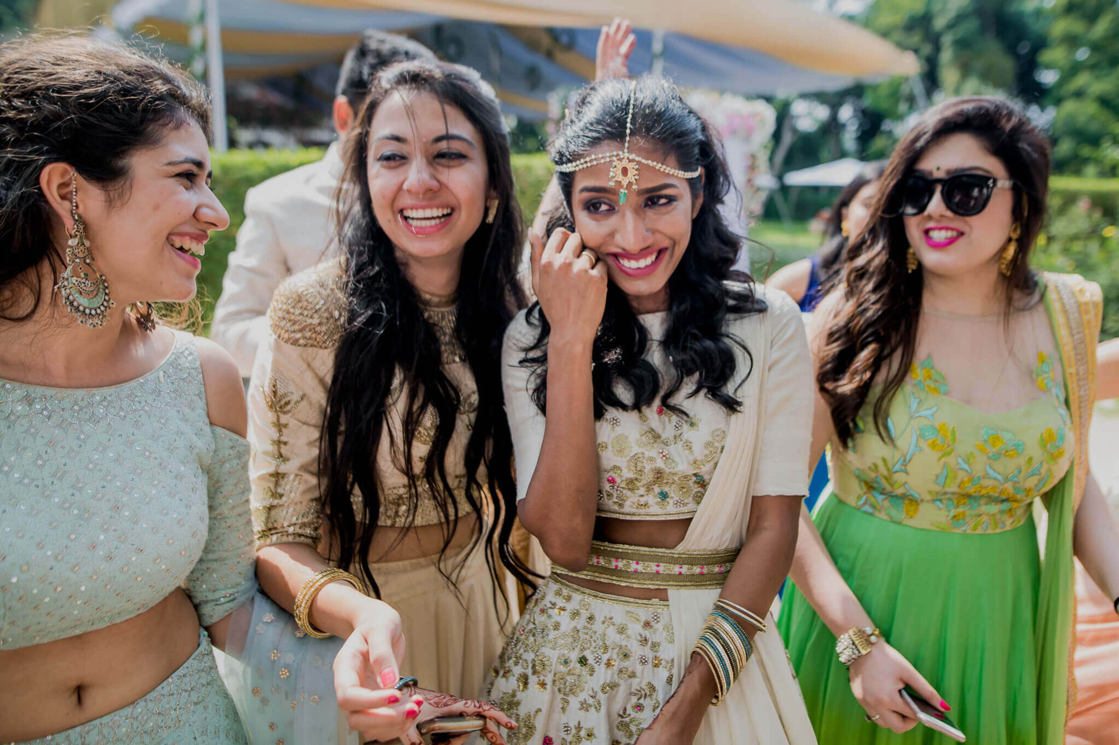 Four women in traditional Indian attire laughing together outdoors at Nepal wedding celebration
