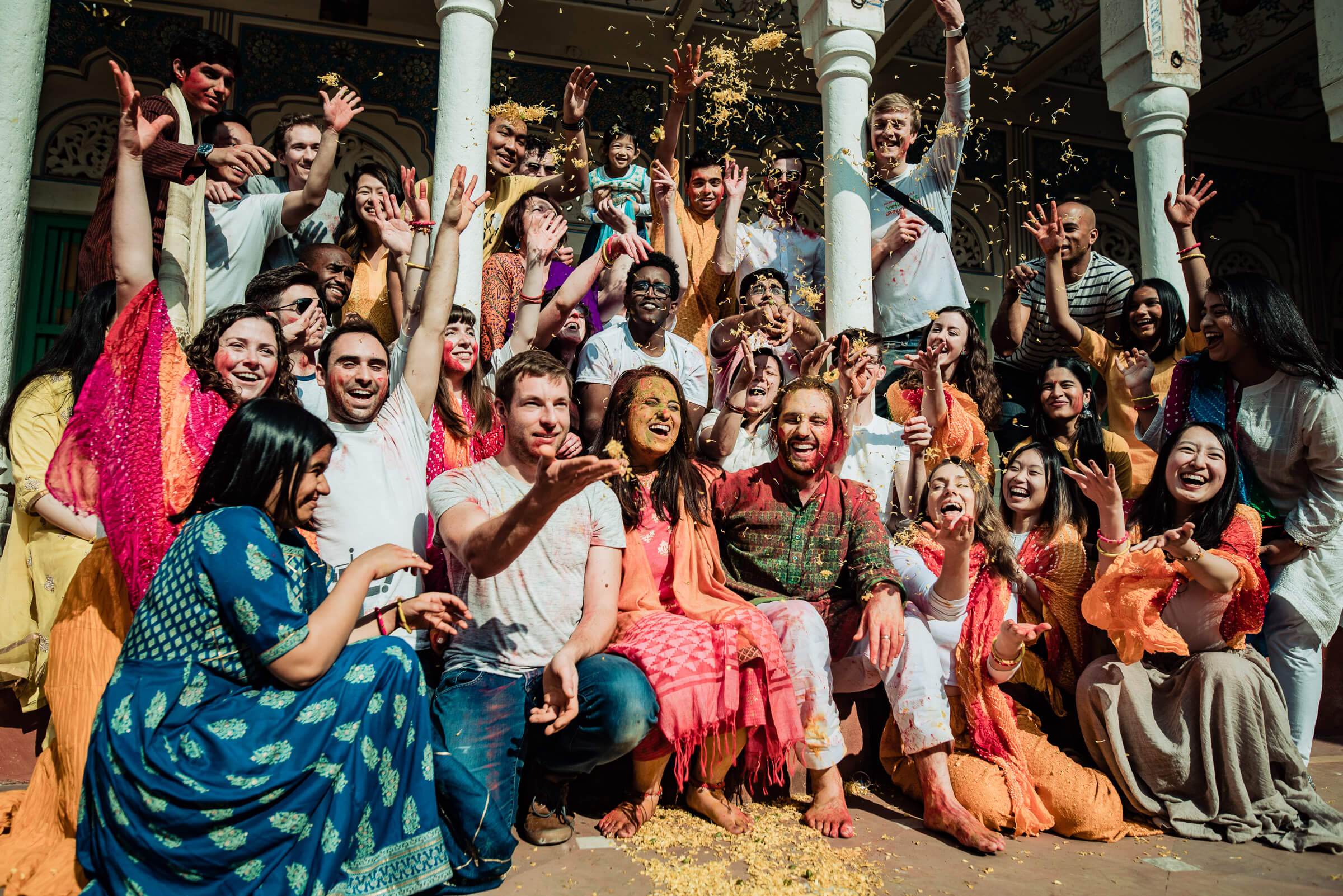 Large wedding celebration group throwing colored powder, Maitrayee and Eric's Rajasthan wedding day