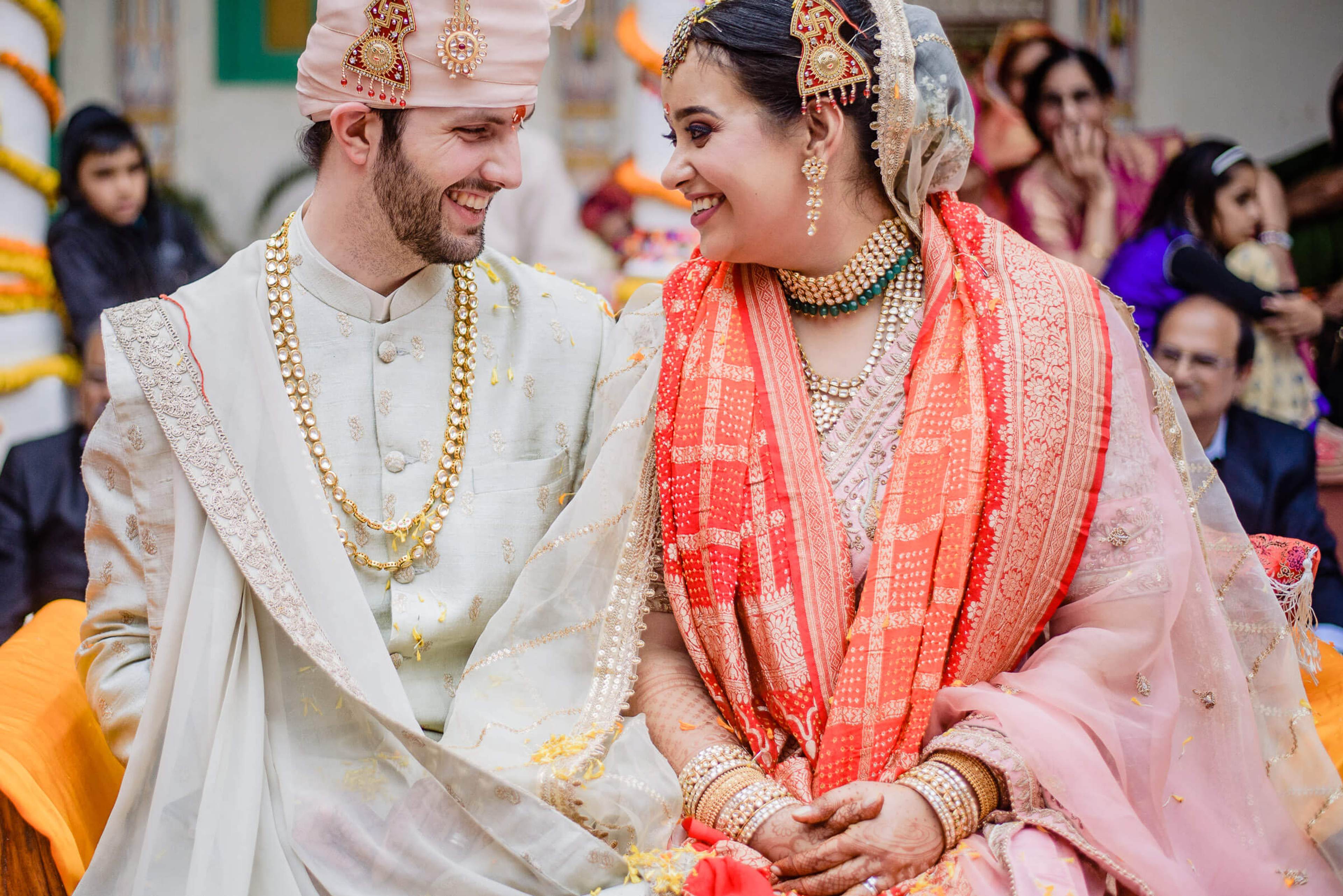 Maitrayee and Eric exchange smiles in traditional Indian wedding attire at their Rajasthan celebration