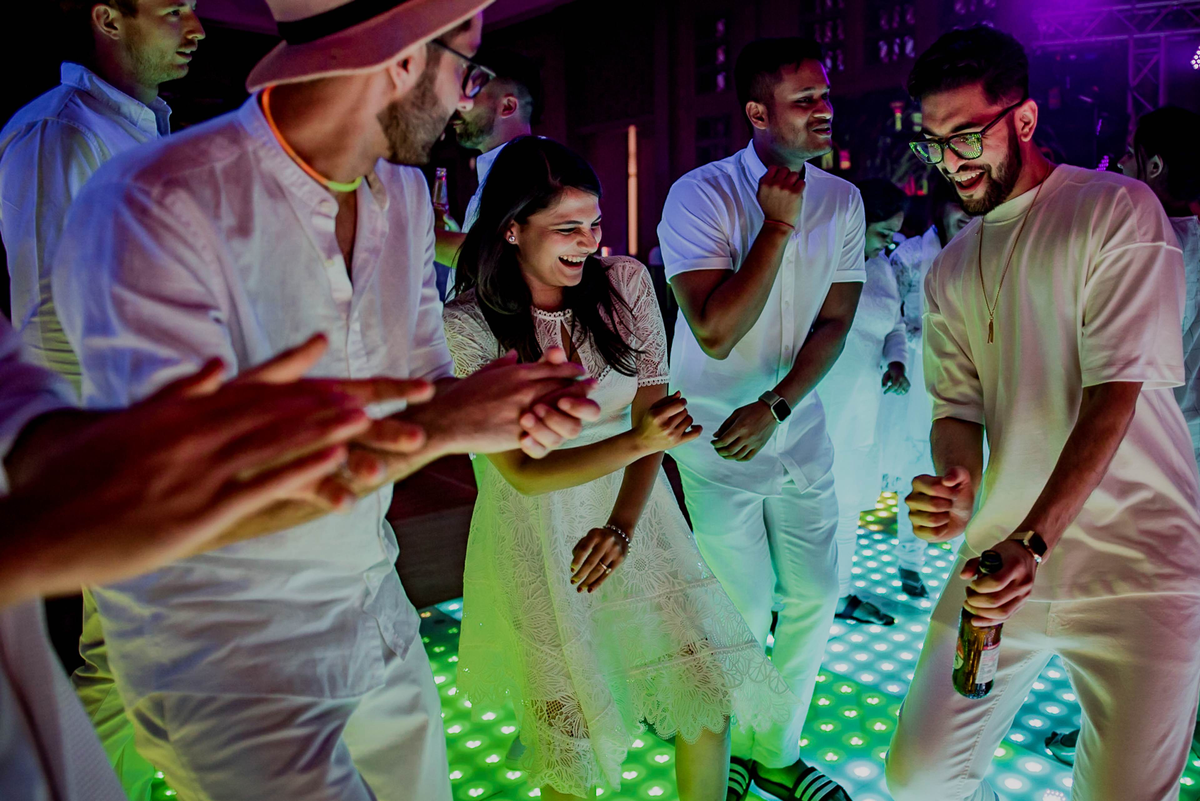 Avani and Srikant dancing with friends in glowing neon lights at their Goa wedding reception