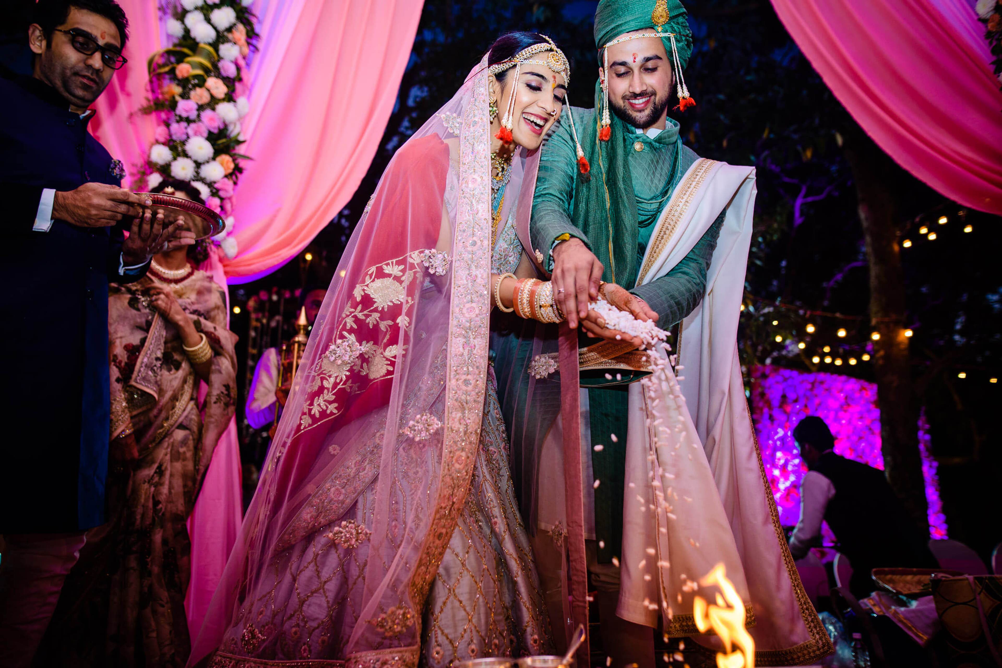 Shreya and Yash in traditional wedding attire at their Mahabaleshwar celebration, surrounded by pink uplighting