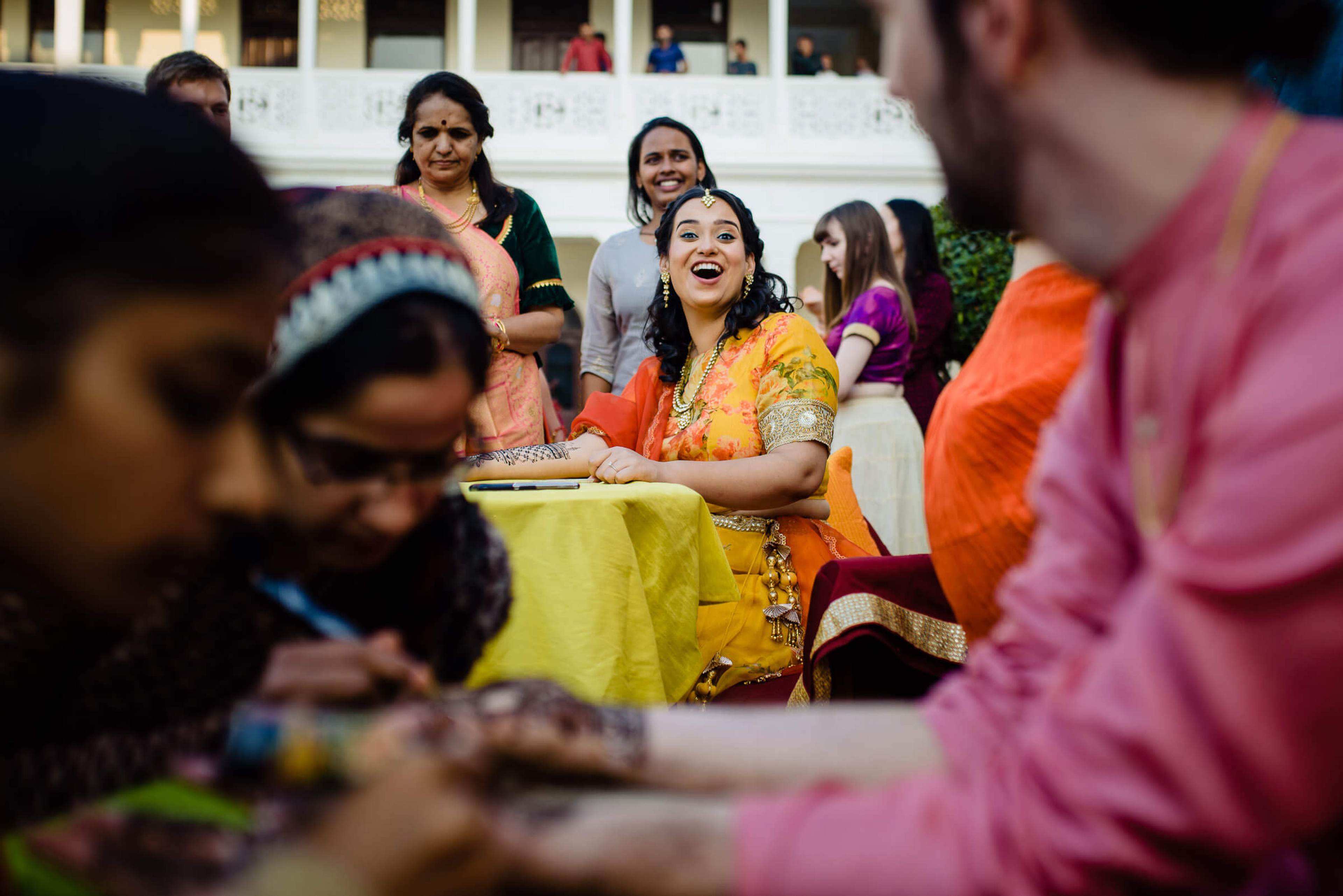 Maitrayee in vibrant yellow and orange traditional dress laughs with family at Rajasthan wedding celebration