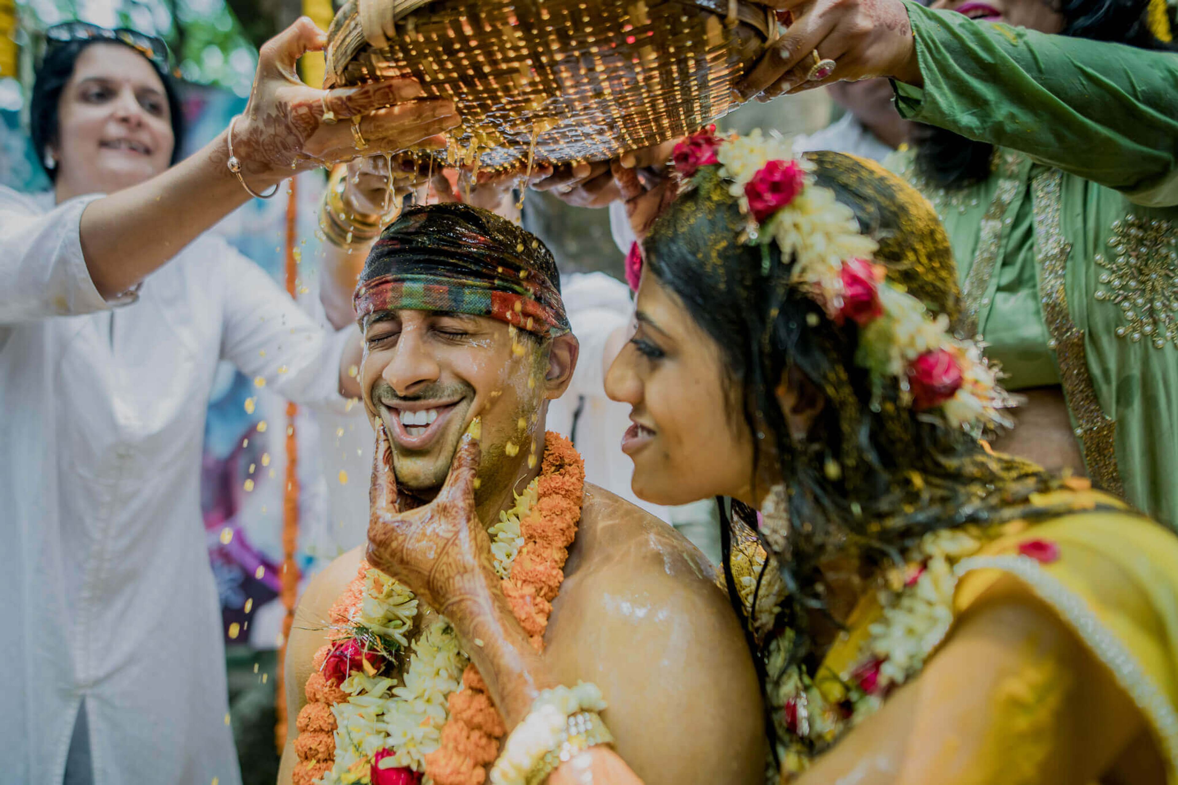 Anu and Raghu laugh as guests shower them with colored powder during a vibrant Nepal wedding celebration