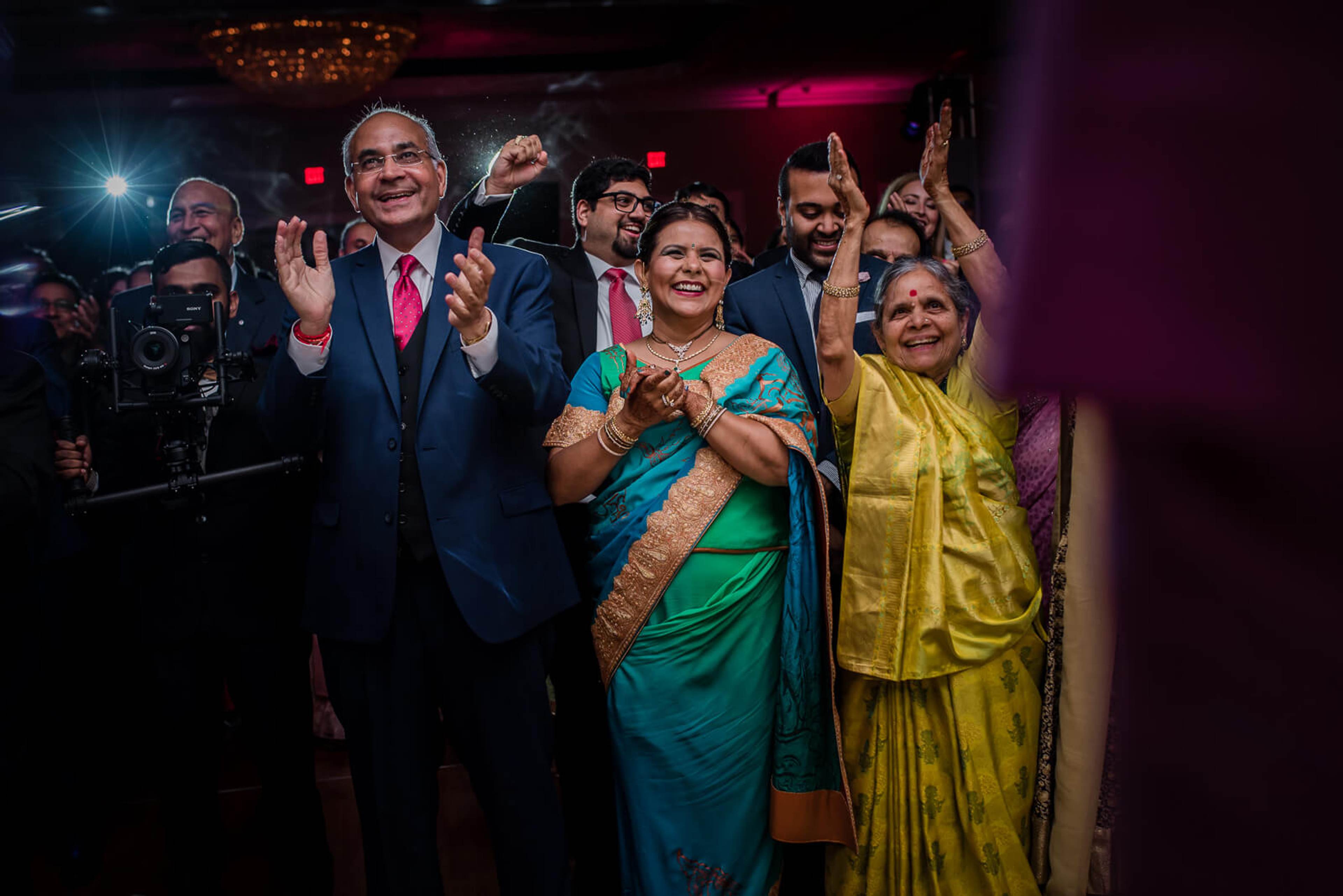 Barkha and Ankit celebrate with family in traditional attire at their New York wedding reception, surrounded by guests and stage lighting