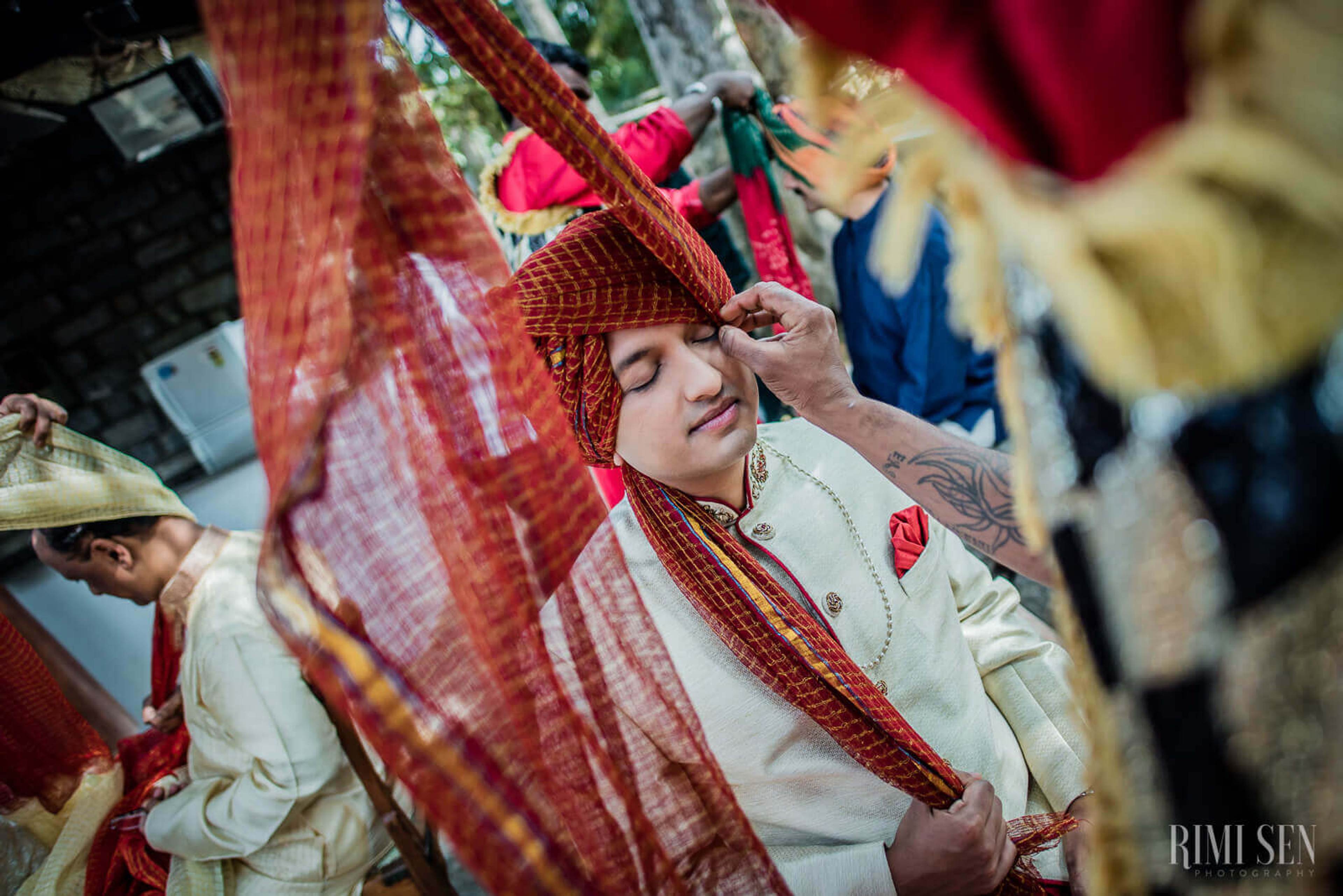 Groom Aniket in cream sherwani adjusting red turban during wedding ceremony in Bangalore