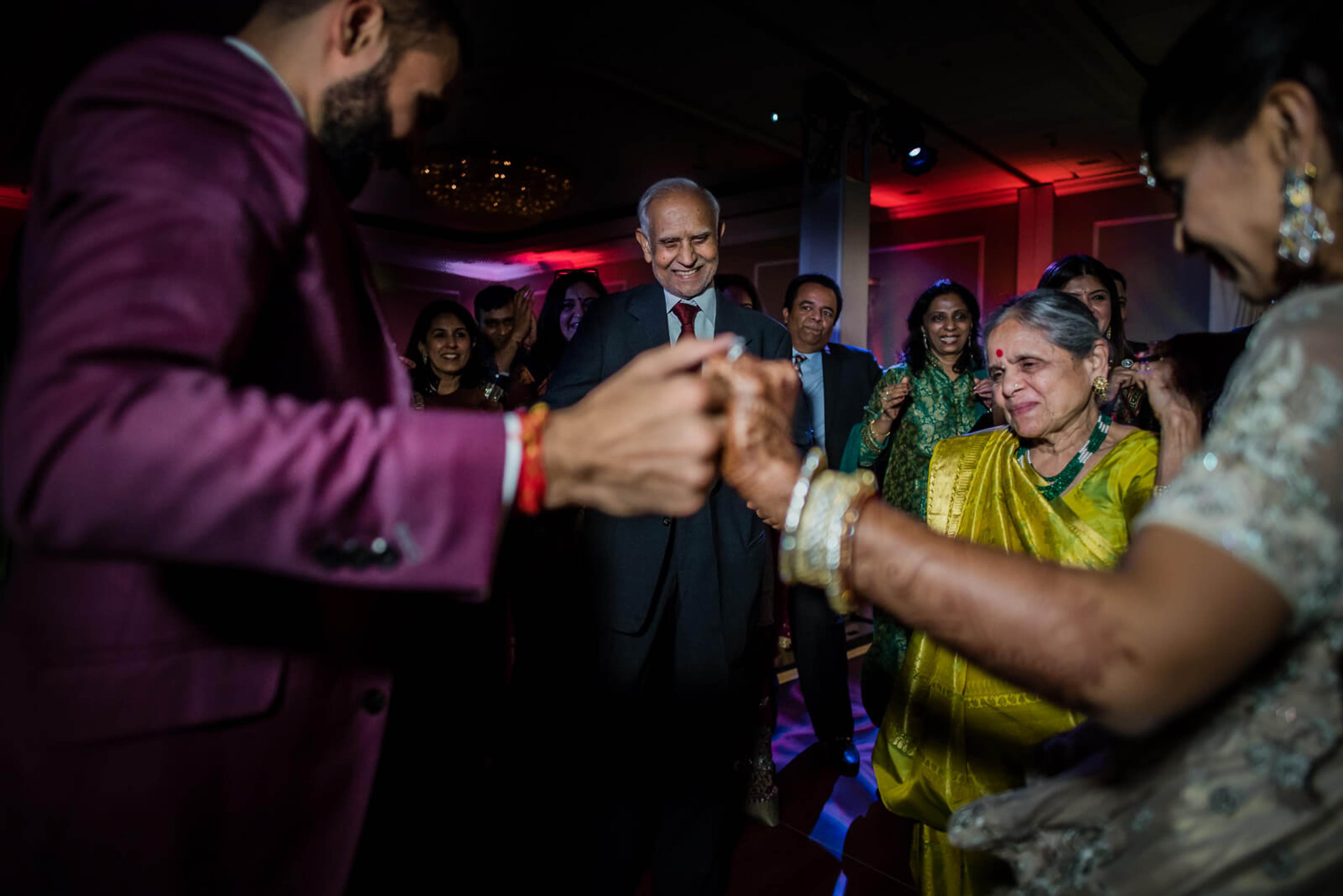 Barkha and Ankit's guests dancing together at their New York wedding reception in colorful attire and purple lighting