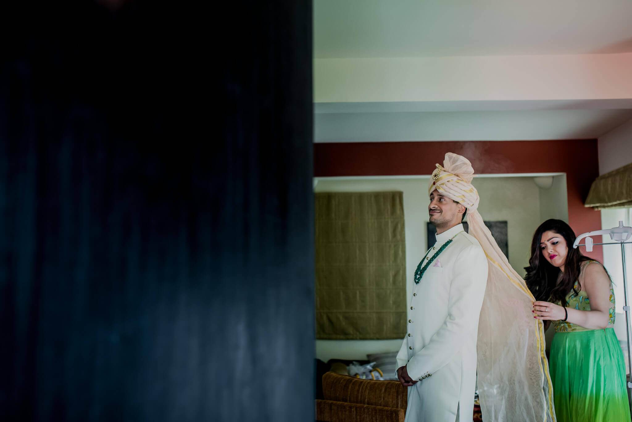 Anu and Raghu share a candid moment as she adjusts his traditional white turban indoors in Nepal
