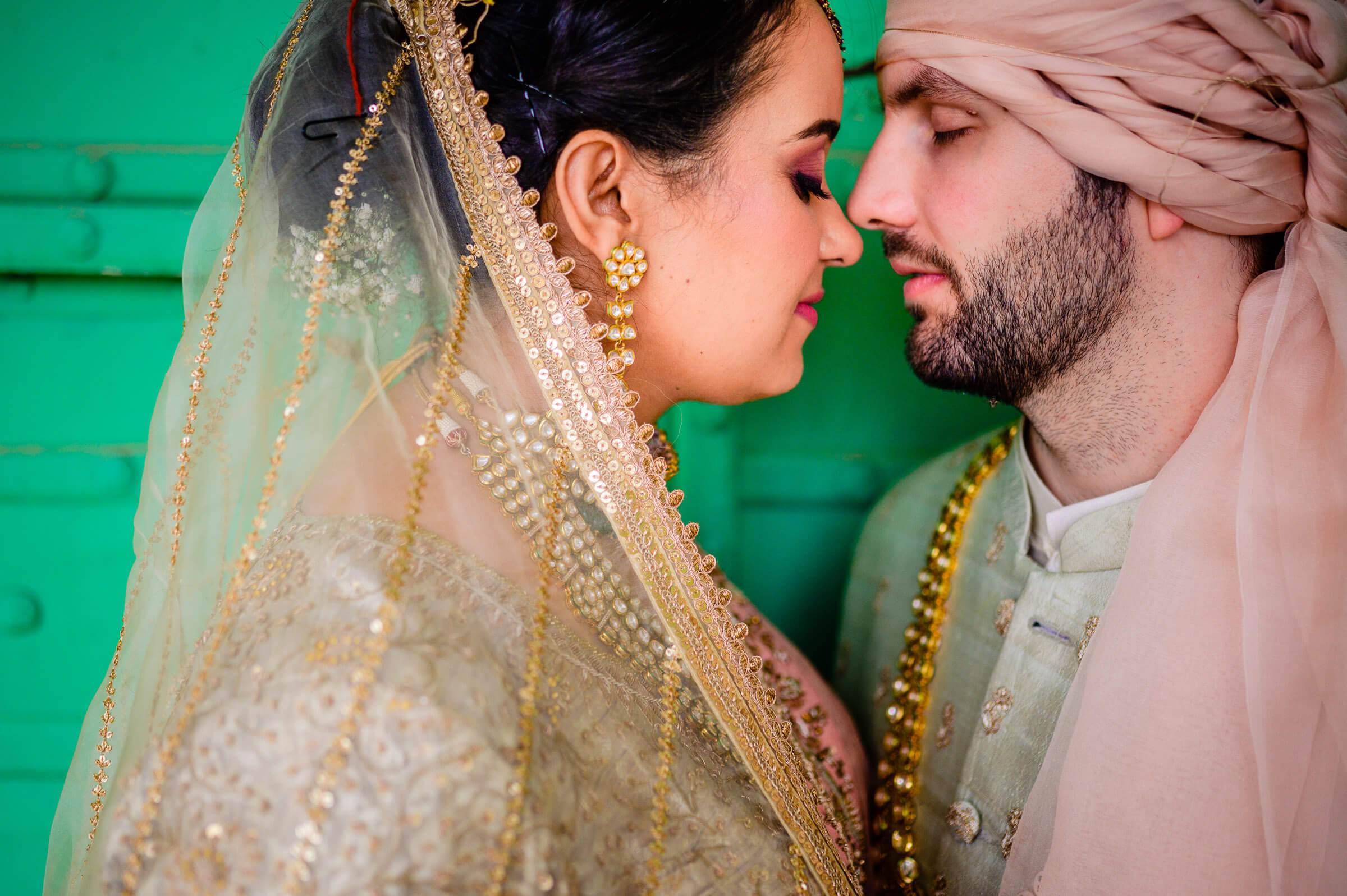 Maitrayee and Eric in traditional wedding attire share an intimate moment against a green backdrop in Rajasthan