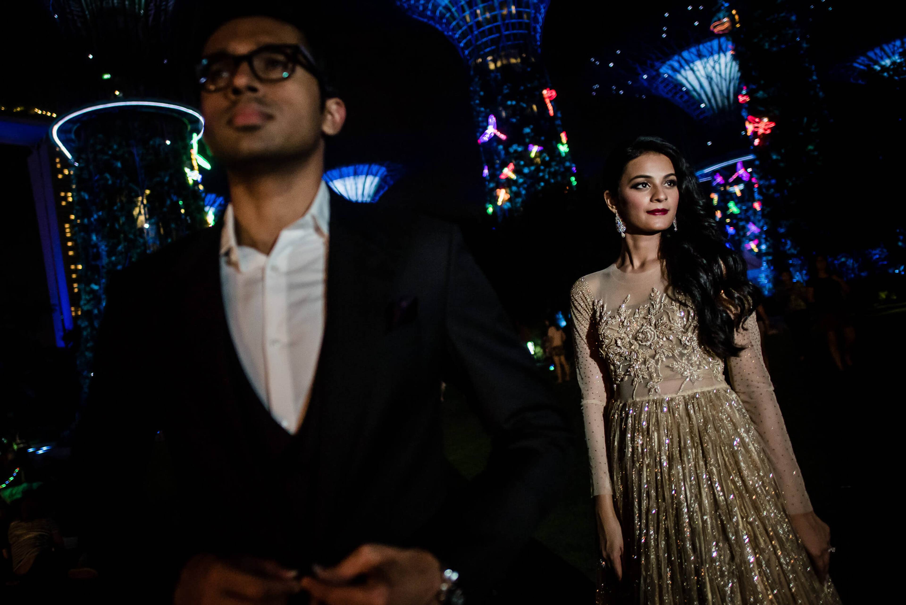 Yash and Disha stand apart in Singapore's illuminated venue, he in black suit, she in embellished gold gown
