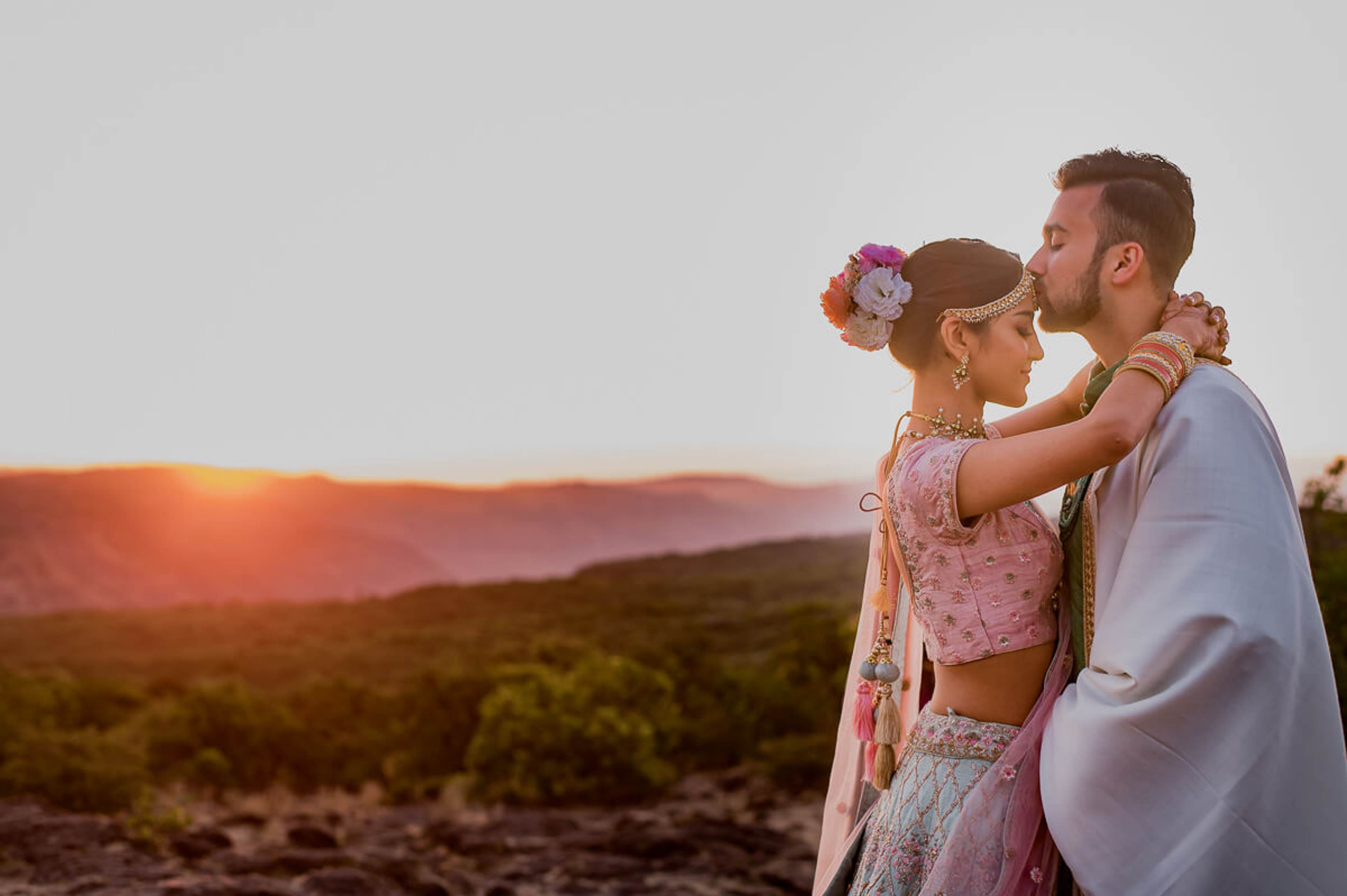 Shreya and Yash embrace at sunset over Mahabaleshwar's rolling valleys, she in pink traditional attire with floral hair piece