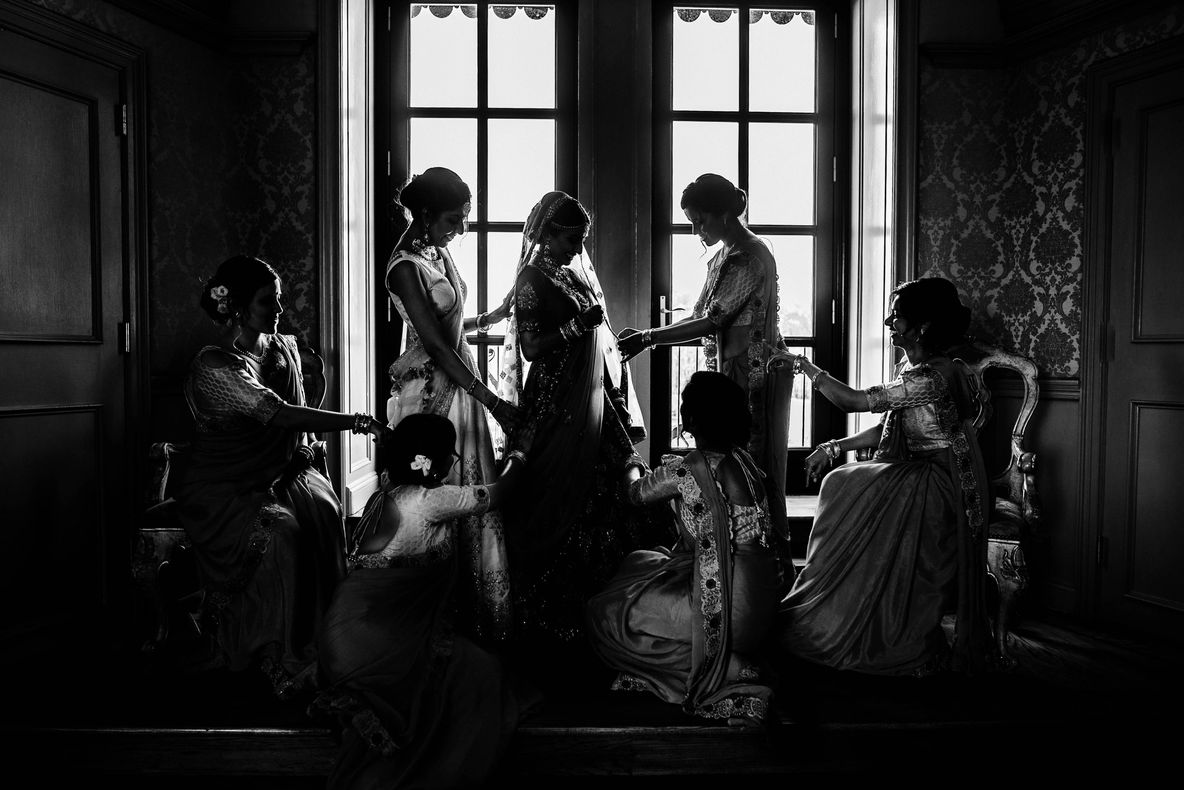 Women in formal attire gathered by ornate windows in elegant black and white interior setting