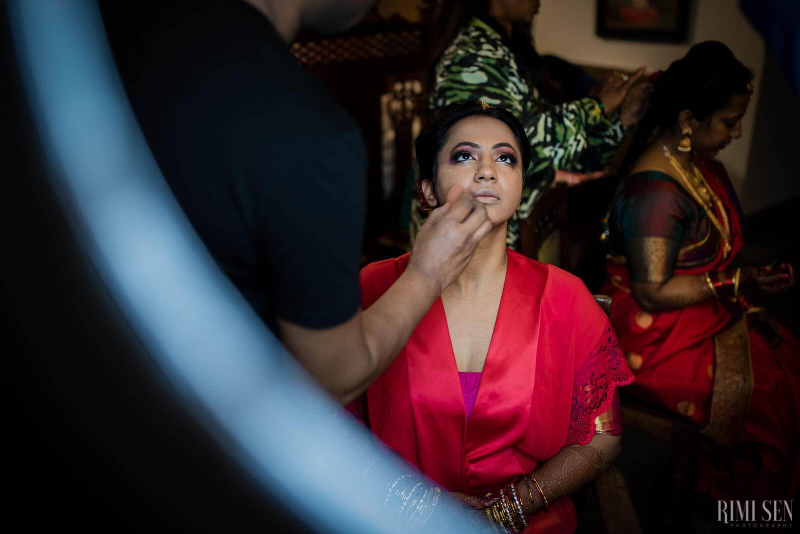 Nivetha in red silk blouse and green headpiece, getting ready for Bangalore wedding ceremony