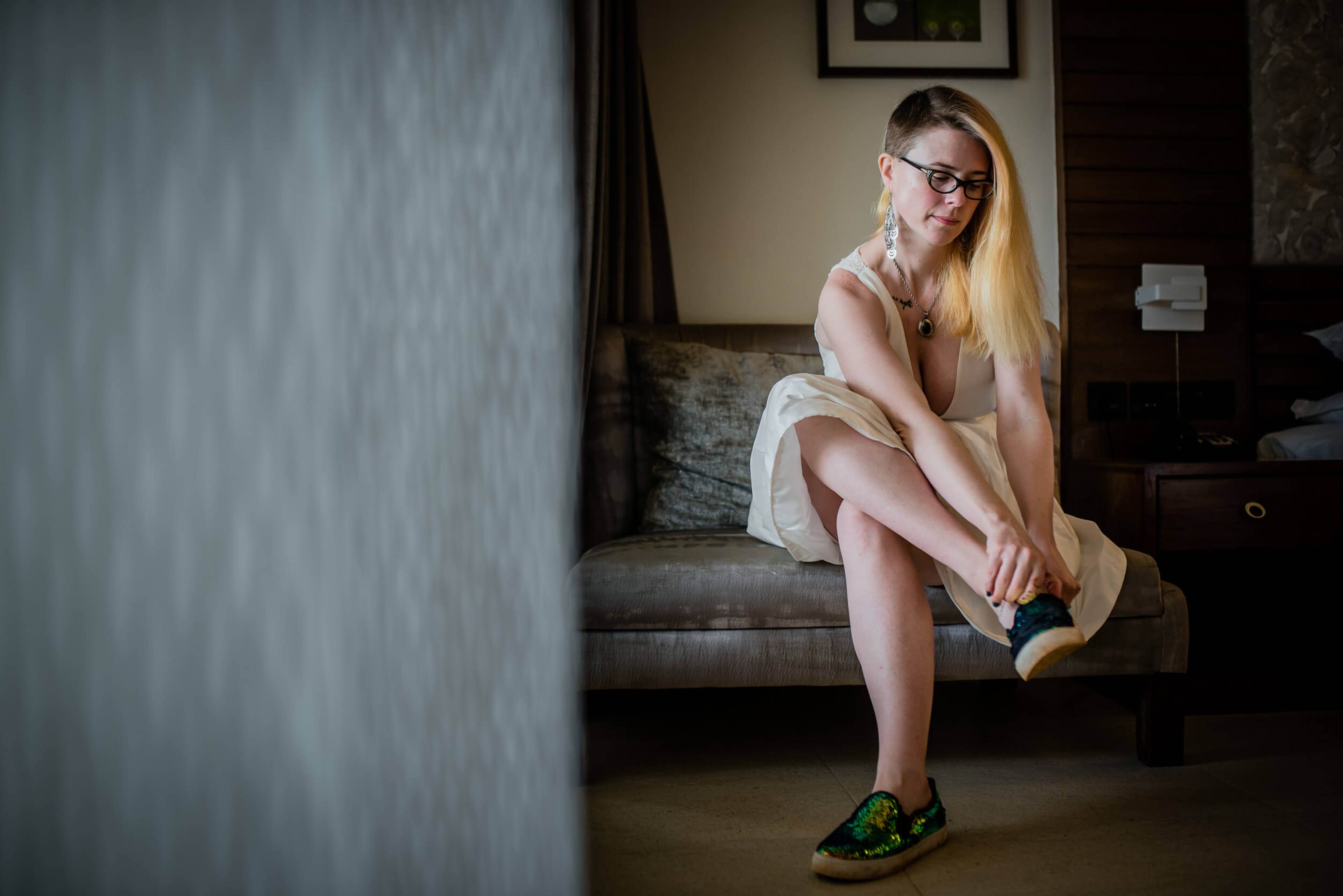 Woman with blonde hair and glasses sitting on couch in warm-lit interior space
