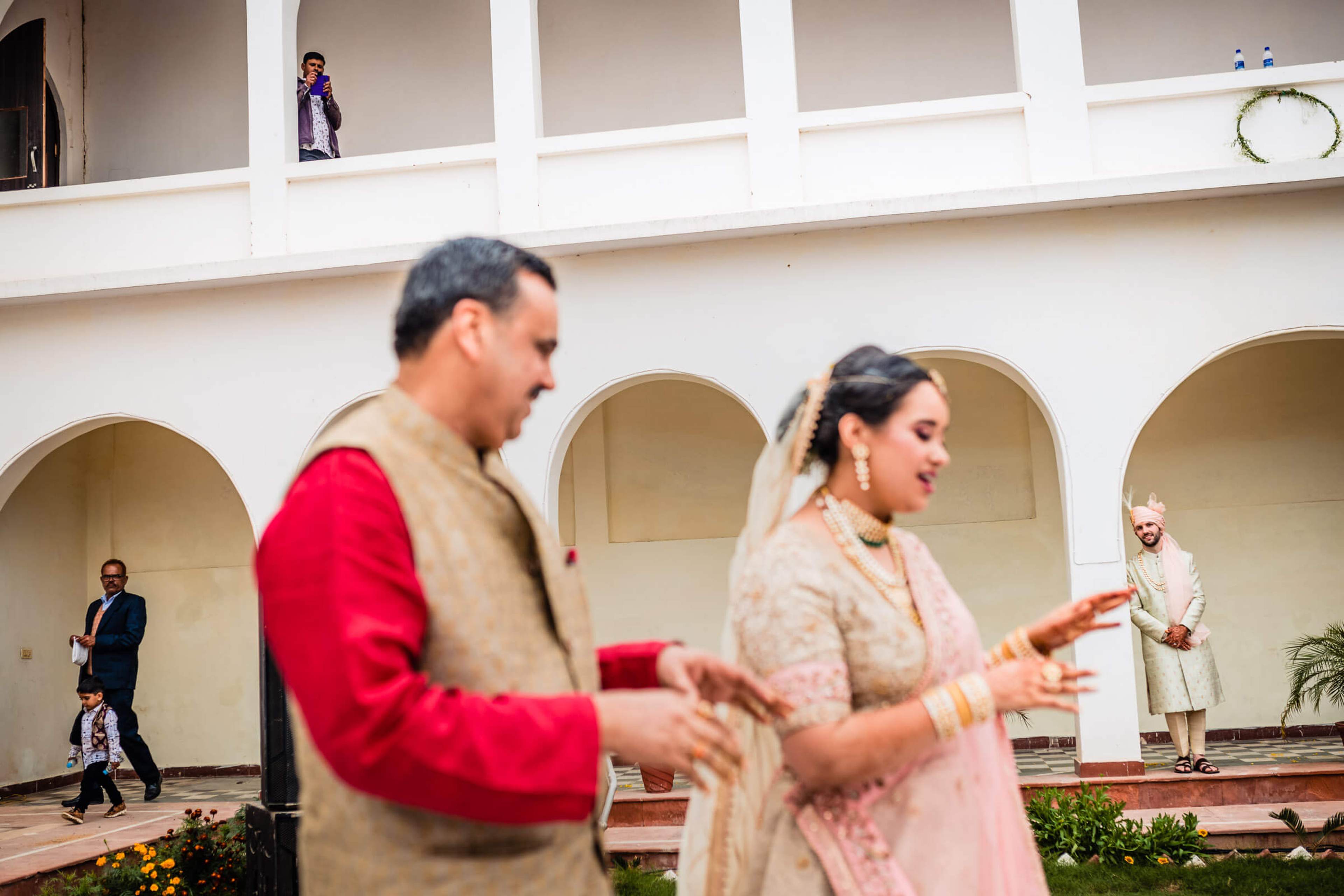 Maitrayee and Eric dance in traditional attire before arched colonnades in Rajasthan