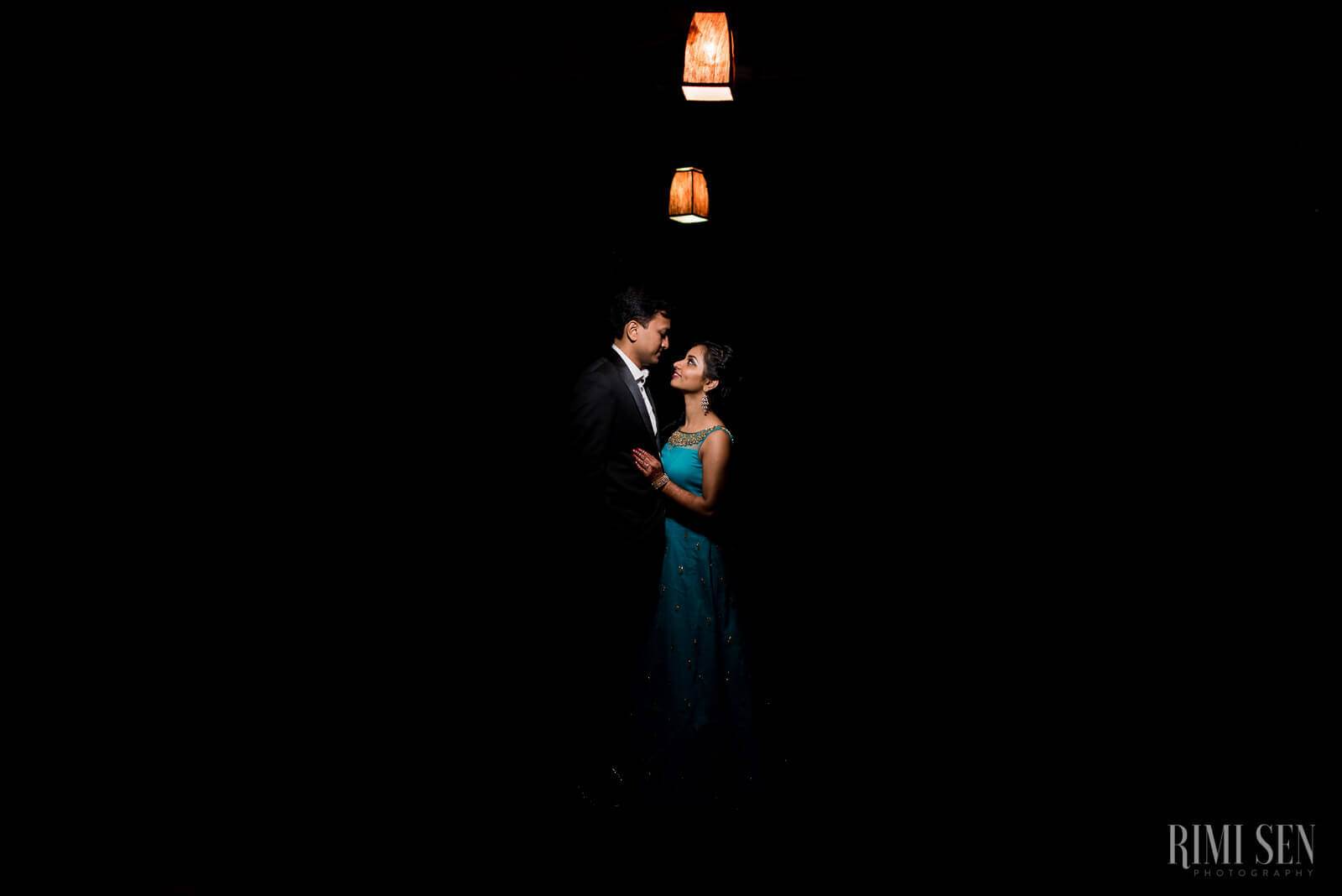 Pooja and Aniket embrace under hanging lanterns against dark night sky in Bangalore