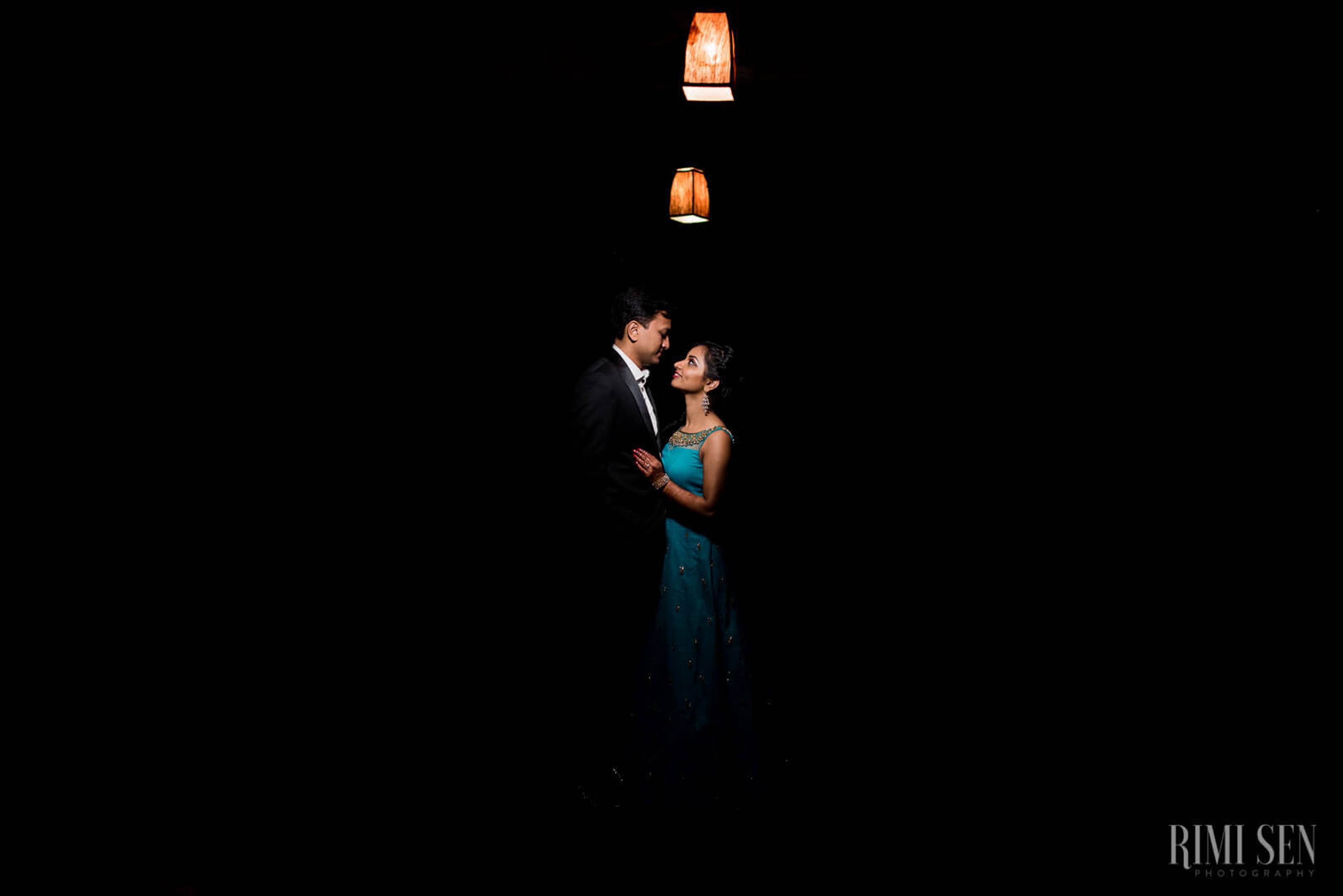 Pooja and Aniket embrace under hanging lanterns against dark night sky in Bangalore